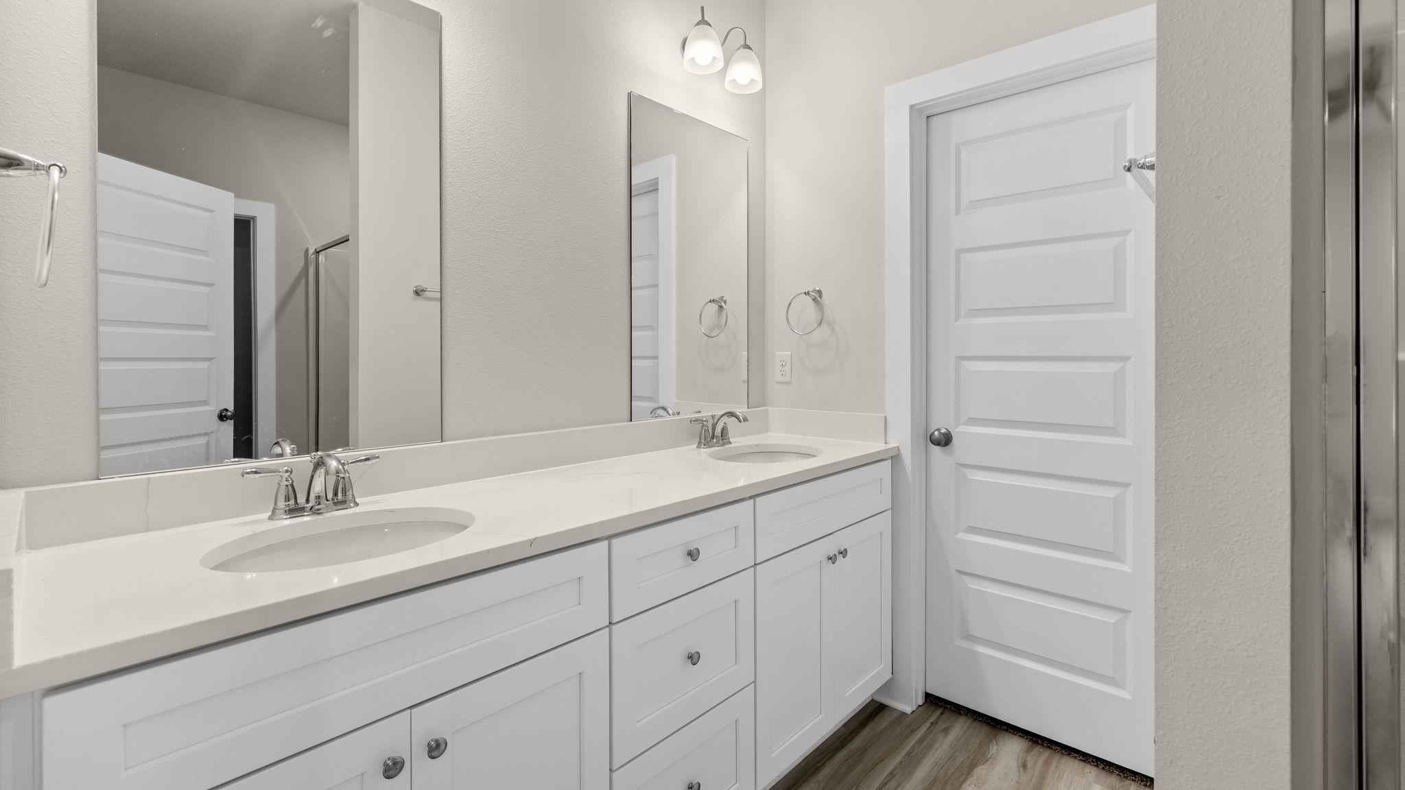 Primary bathroom with double vanity quartz countertops and white cabinets and shower and closet with EVP flooring.