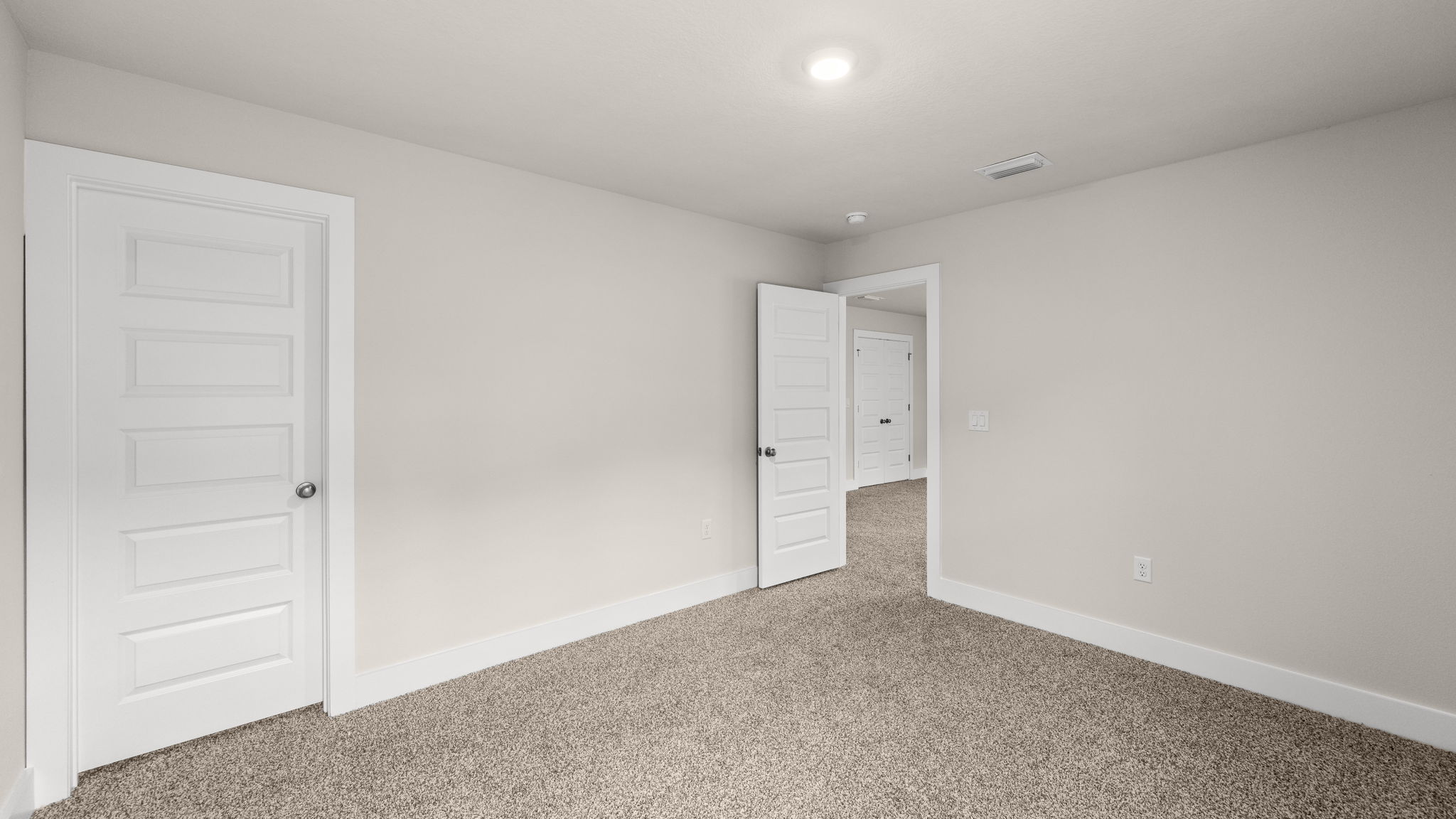 Bedroom with carpet flooring and closet and bathroom entrance.