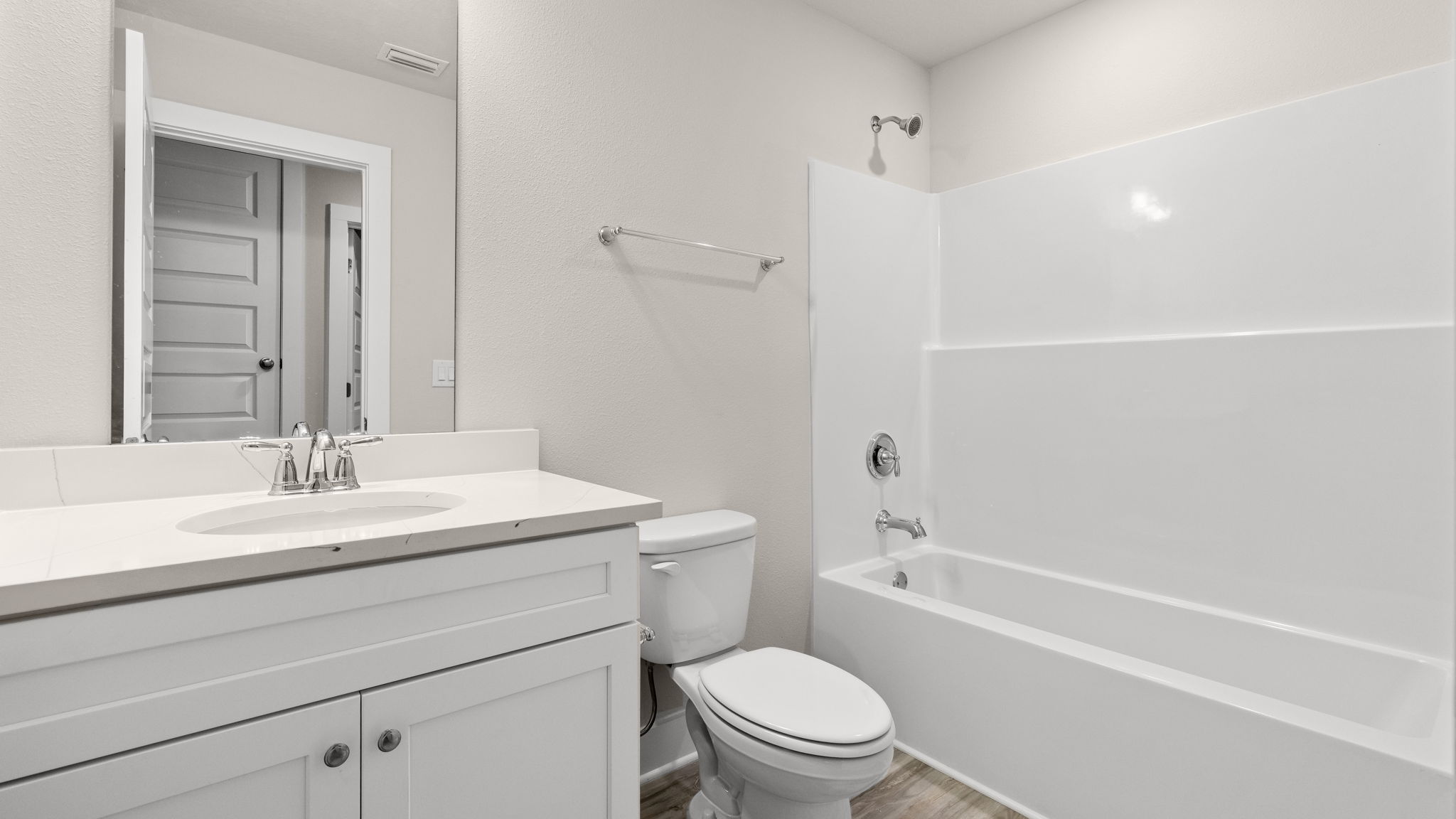 Bathroom with single vanity quartz countertops and white cabinets and toilet and shower.