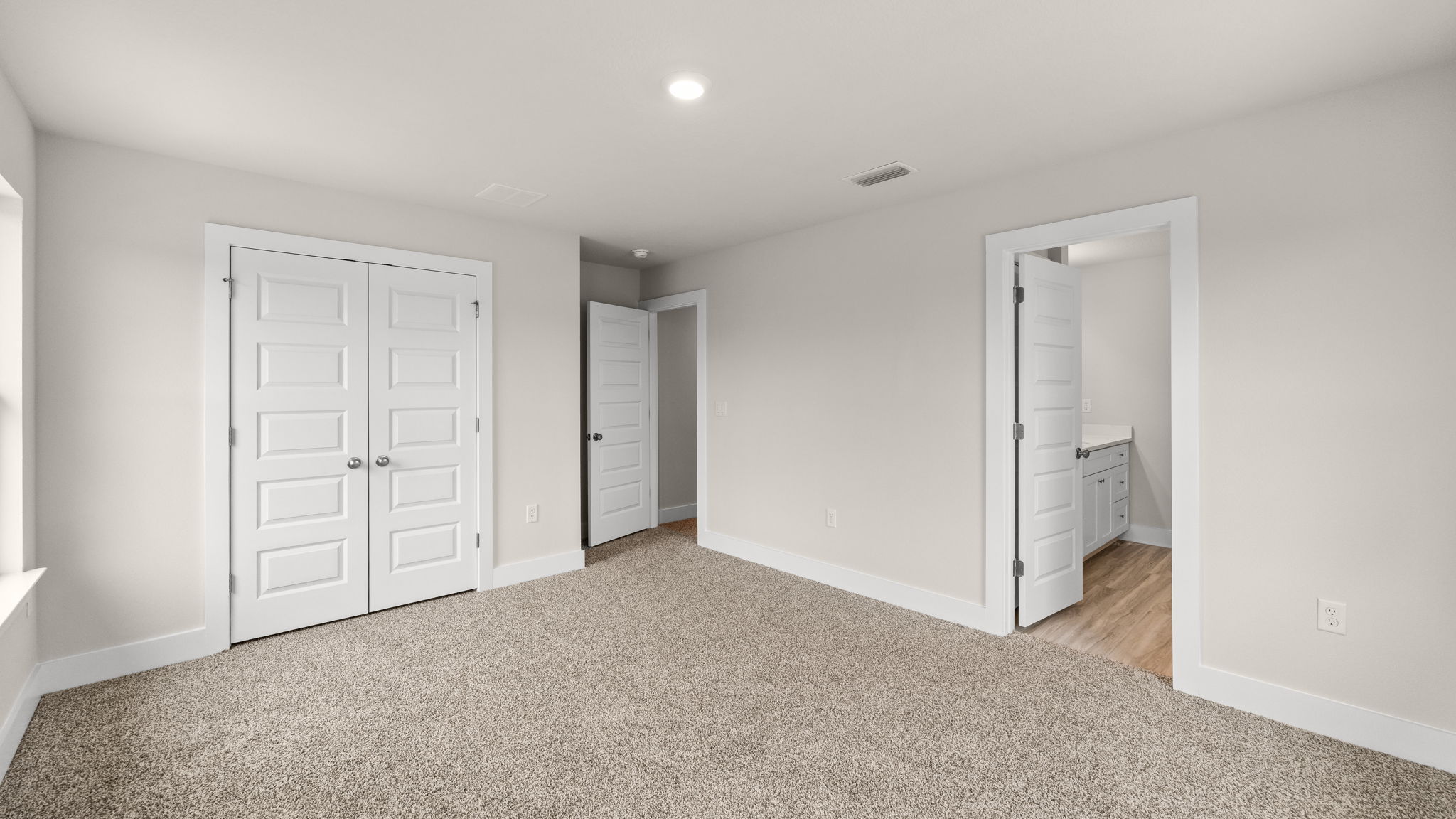 Bedroom with carpet flooring and closet and bathroom entrance.