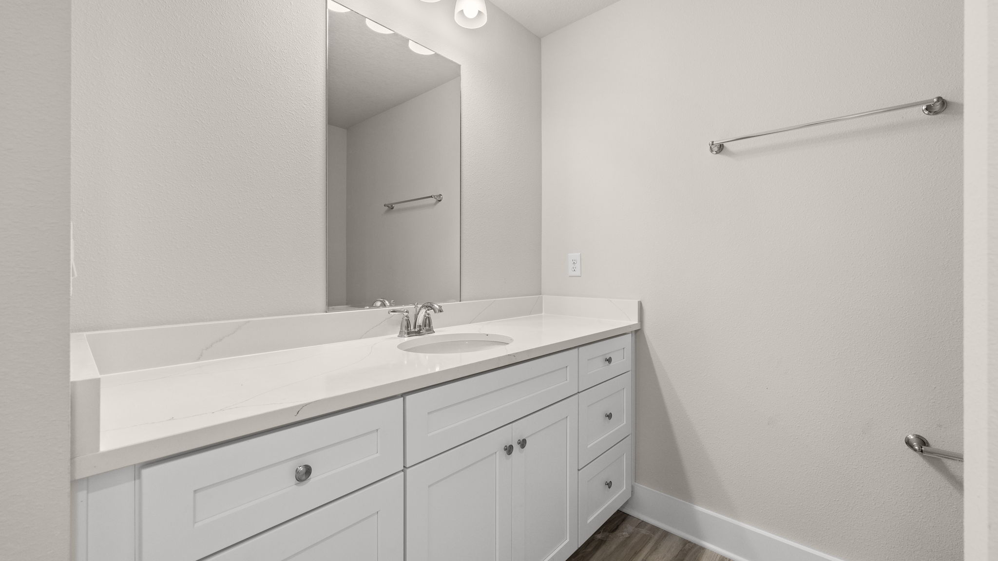 Bathroom with single vanity quartz countertops and white cabinets.