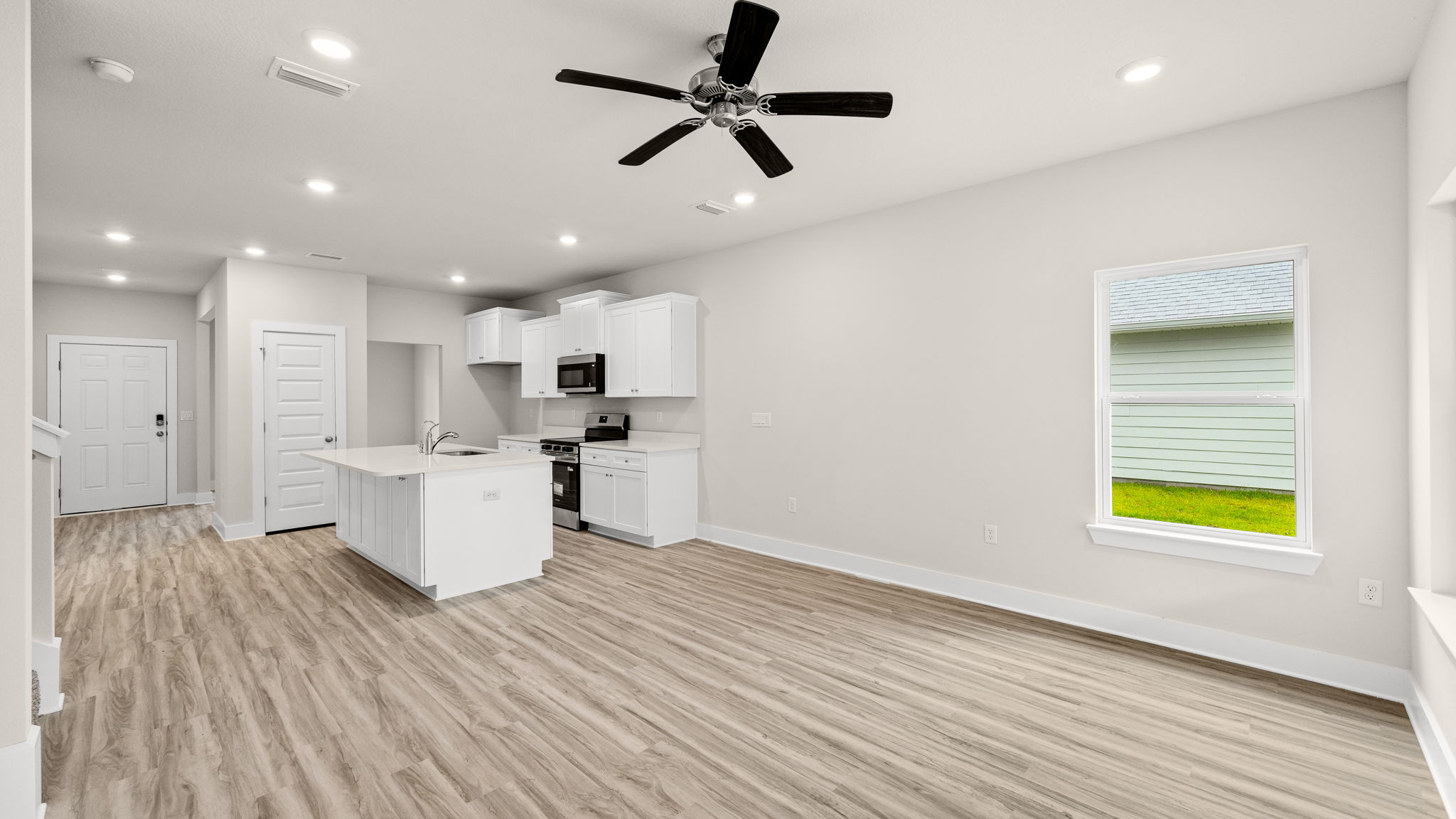 Living room with ceiling fan and EVP flooring and window.