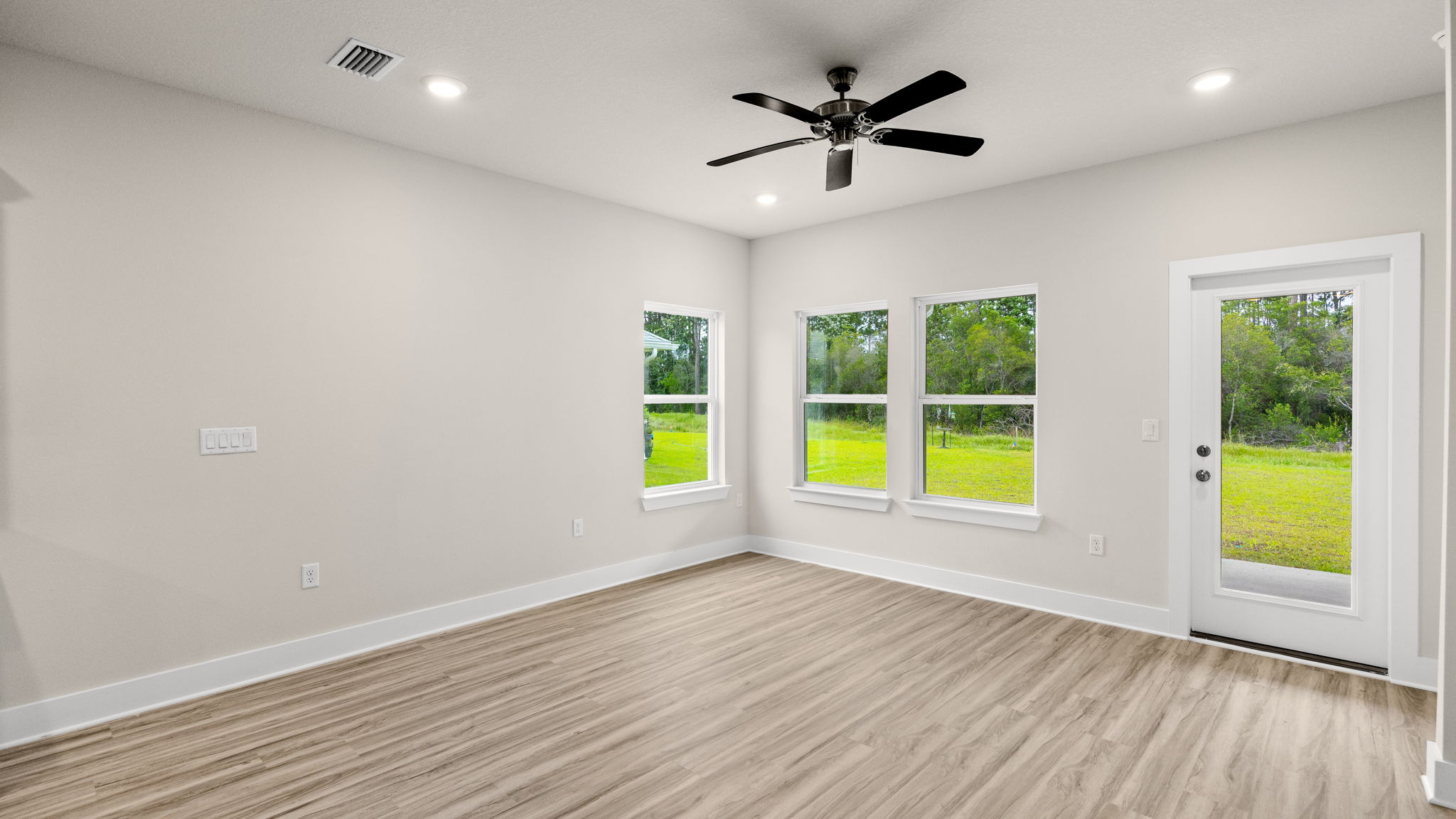 Living room with ceiling fan and EVP flooring and back door.