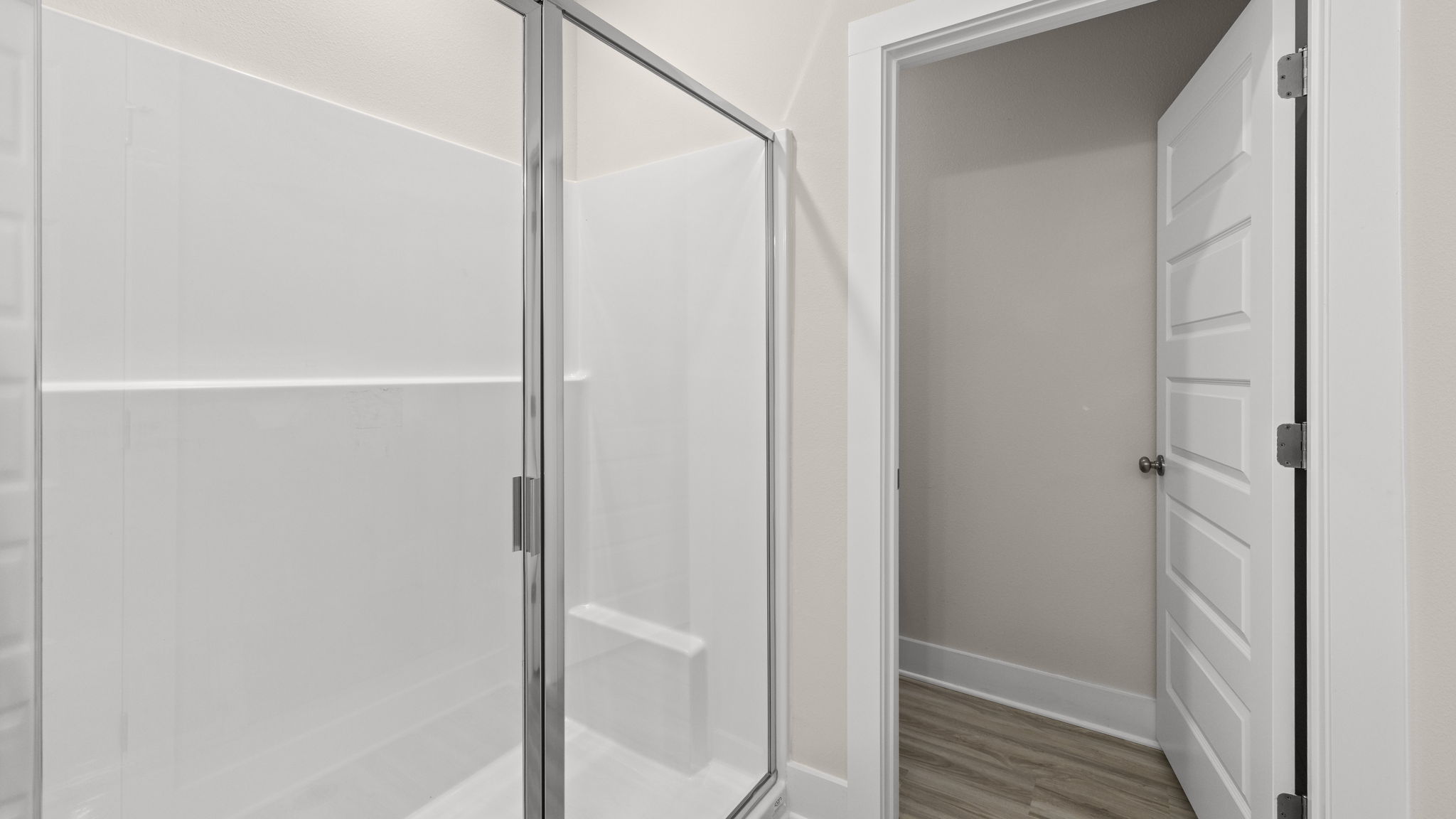 Primary bathroom with double vanity quartz countertops and white cabinets and shower and closet with EVP flooring.