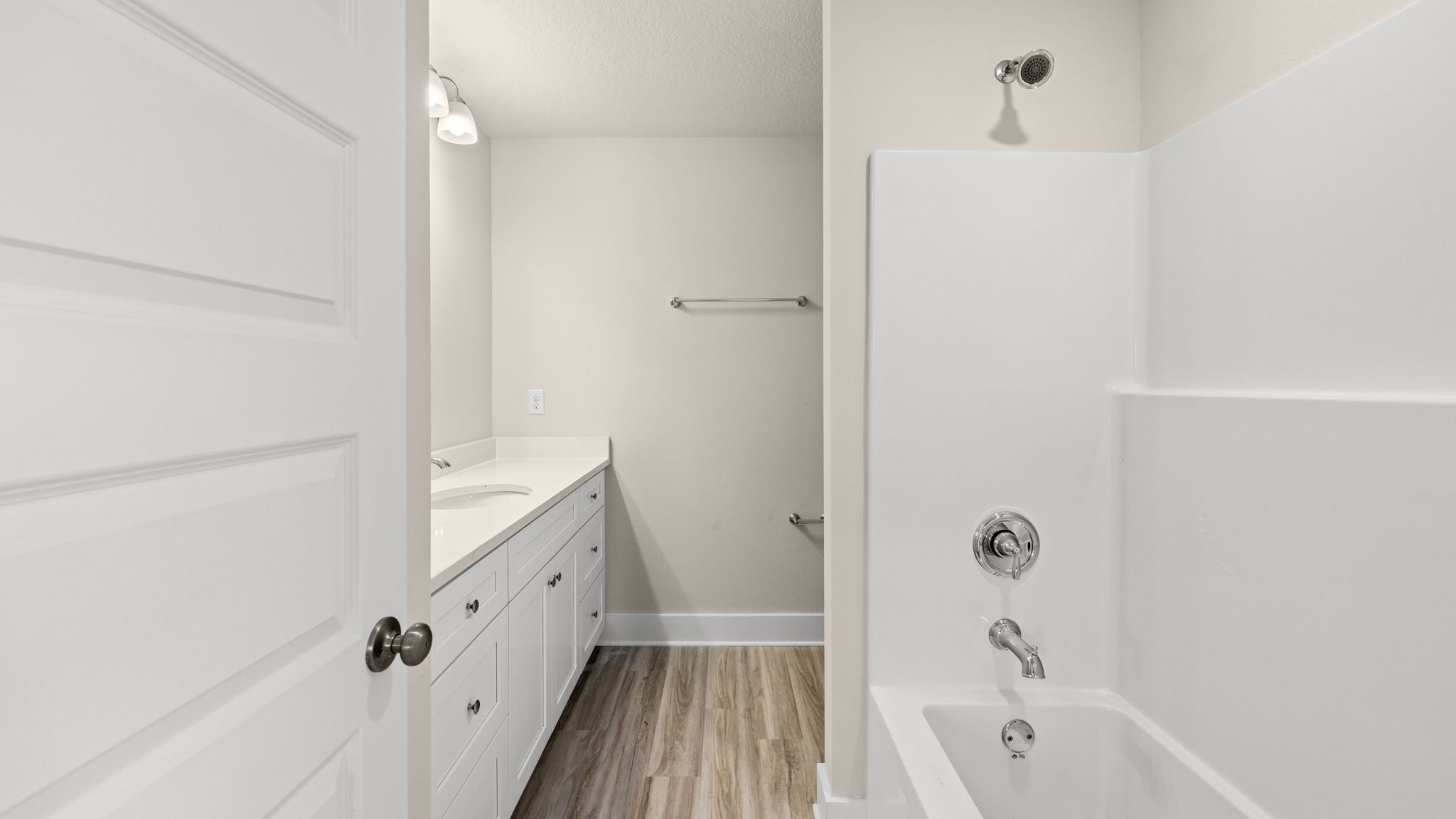 Bathroom with single vanity quartz countertops and white cabinets and toilet and shower.