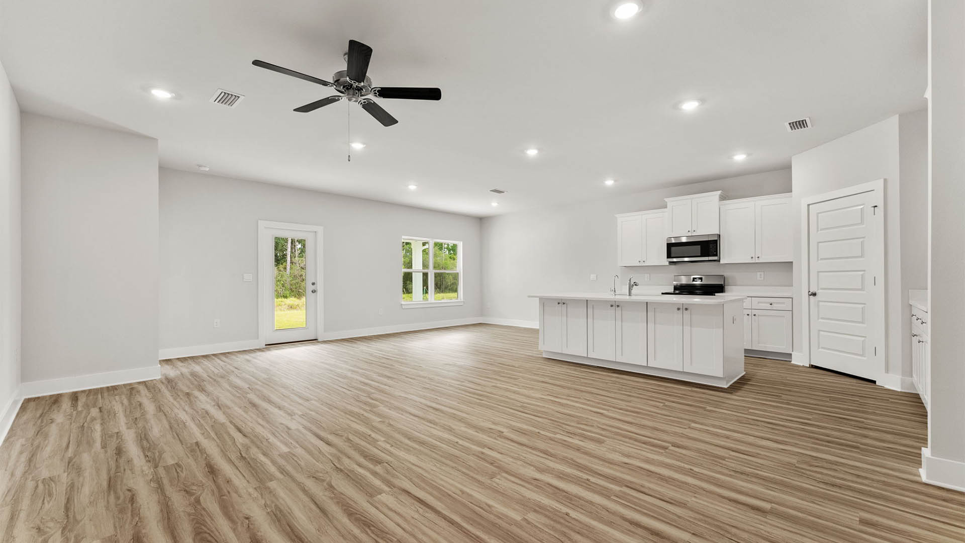 Open Living room with EVP flooring and ceiling fan and kitchen island with quartz countertops.