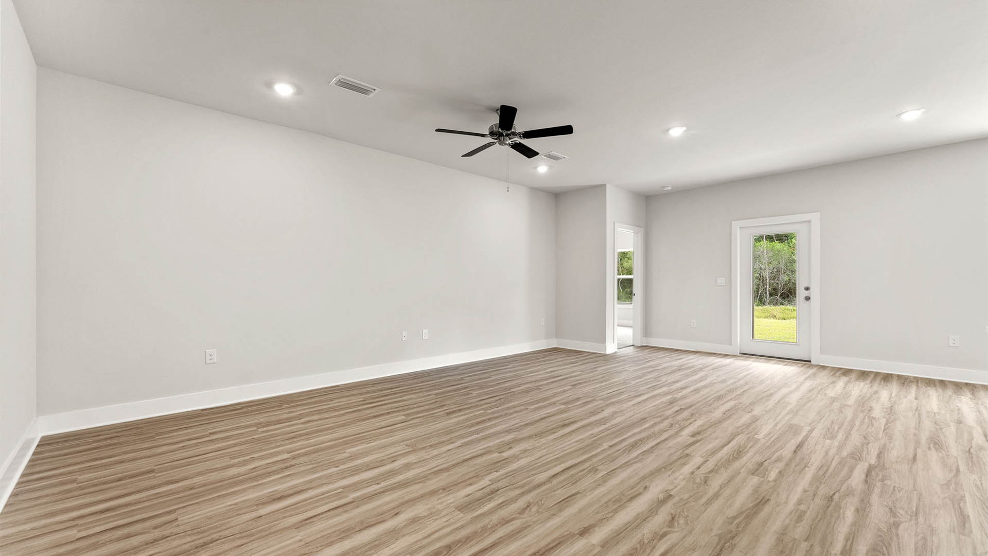 Open Living room with EVP flooring and ceiling fan and back door.