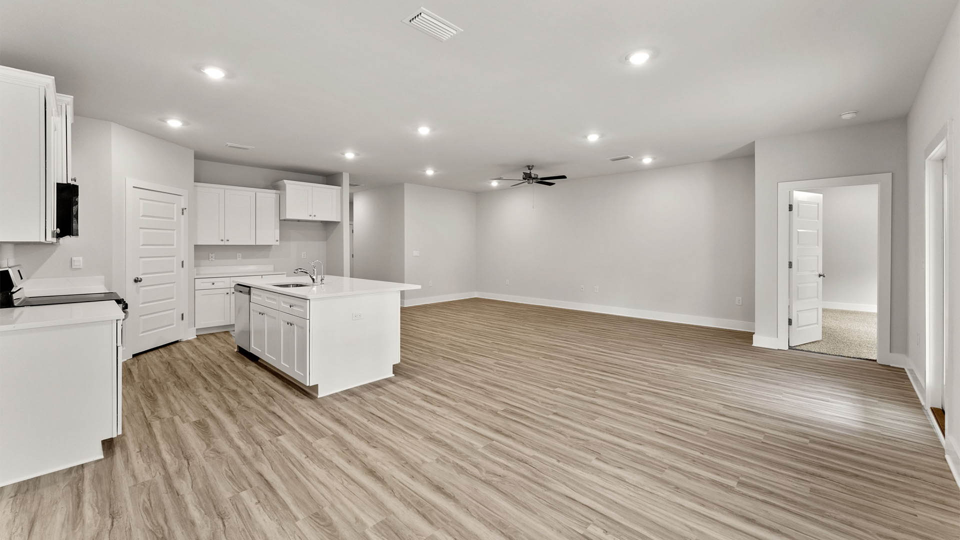Open Living room with EVP flooring and ceiling fan and kitchen island with quartz countertops.