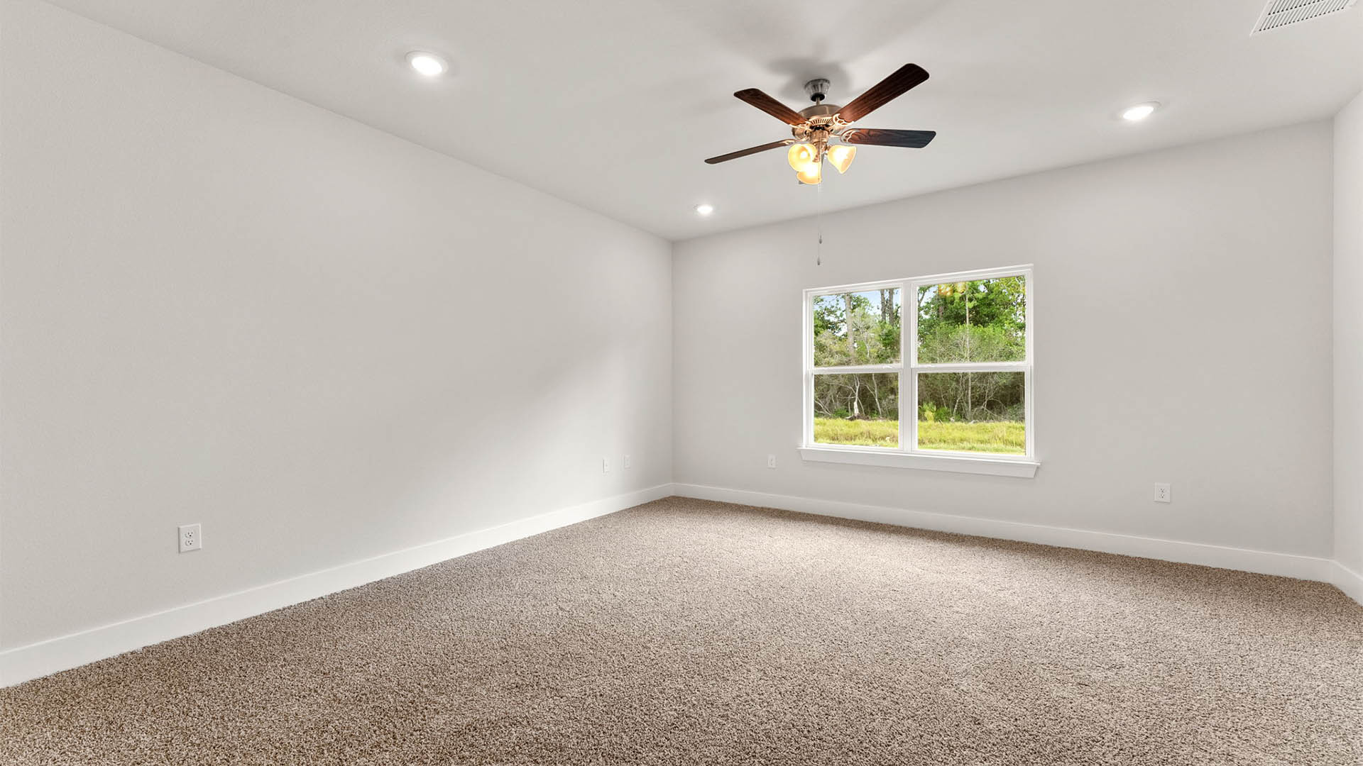 Primary bedroom with carpet floors and ceiling fan and windows.