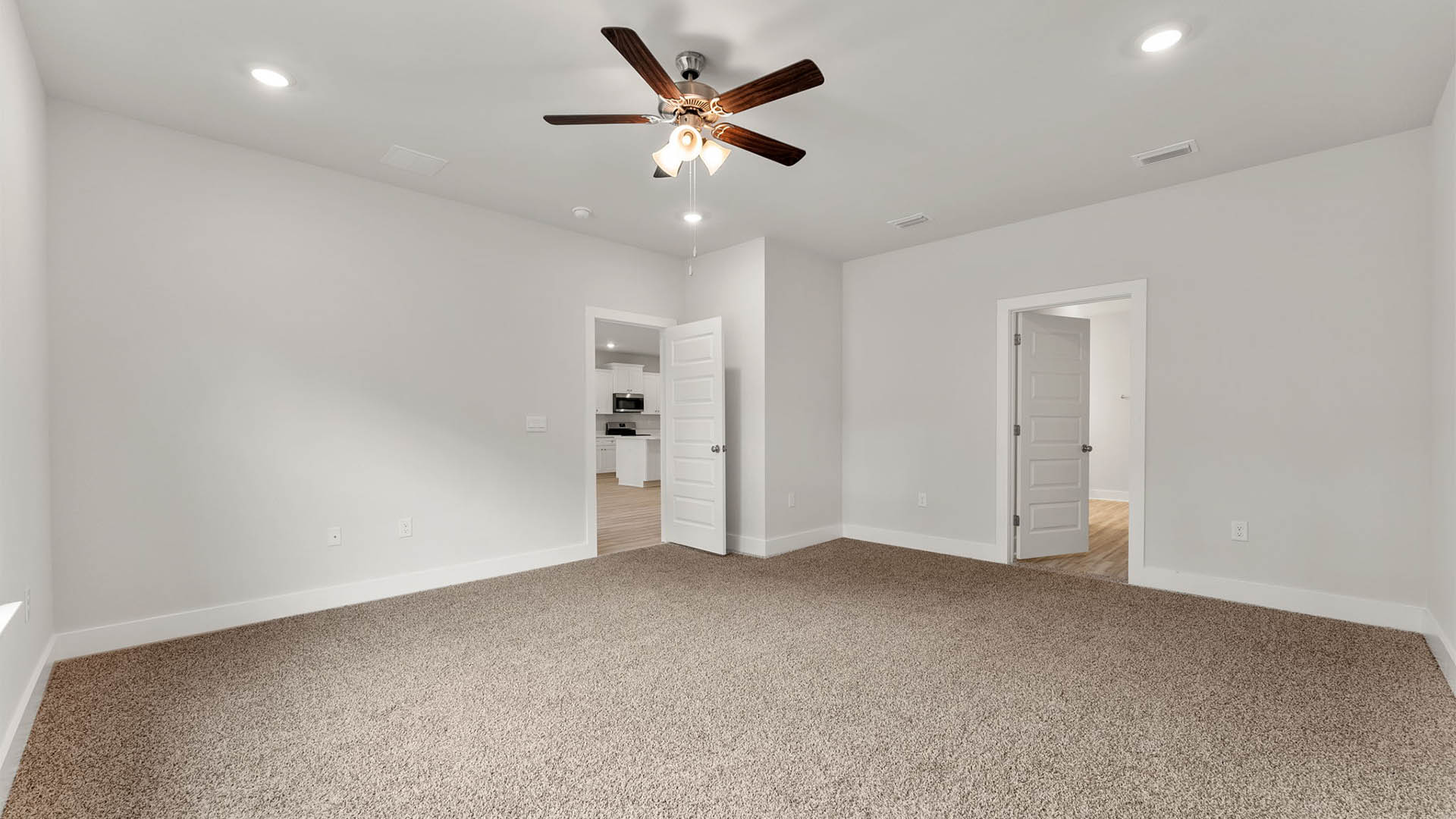 Primary bedroom with carpet floors and ceiling fan and bathroom.