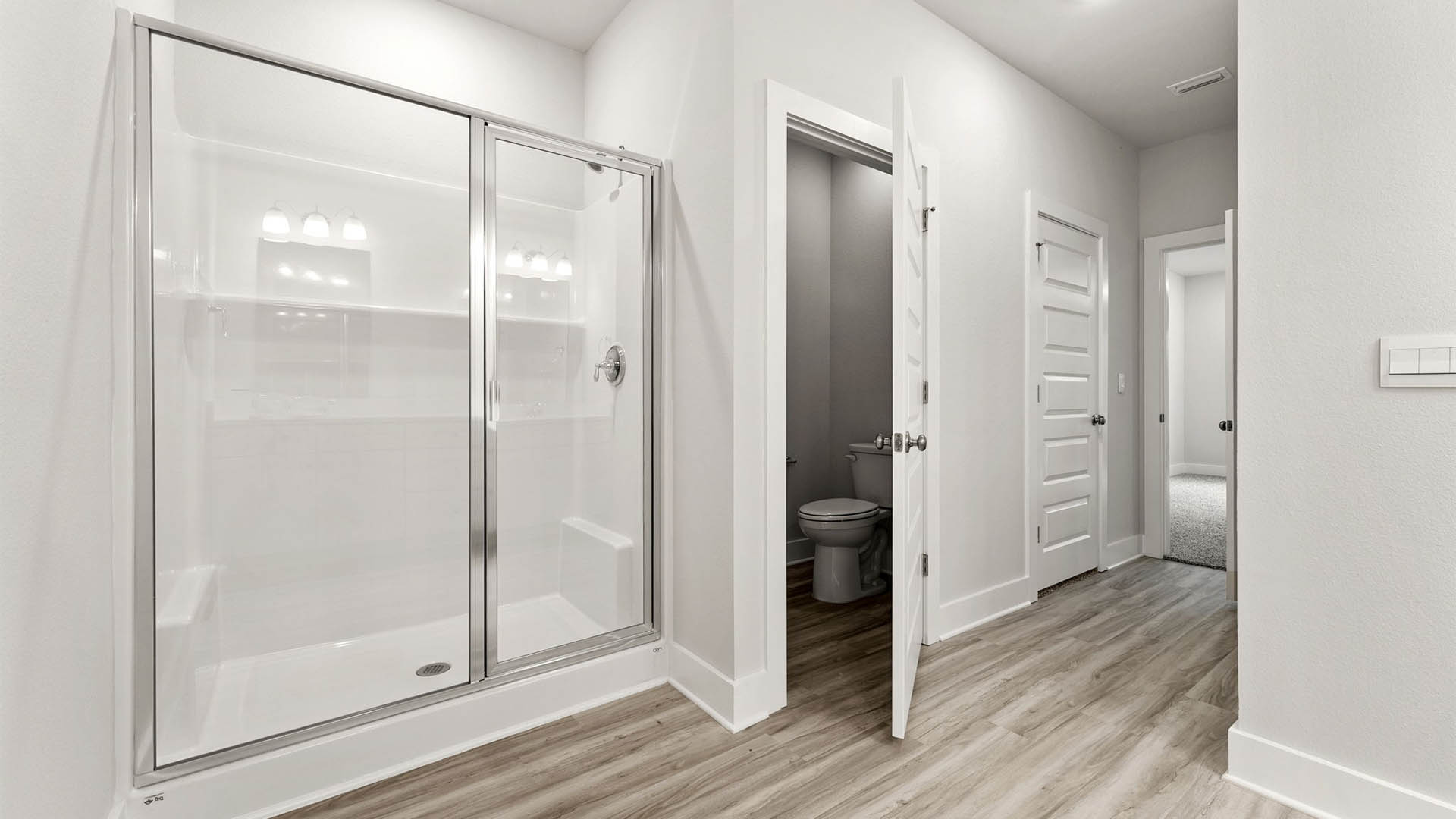 Primary bathroom with EVP flooring and shower with glass door and walk-in closet.