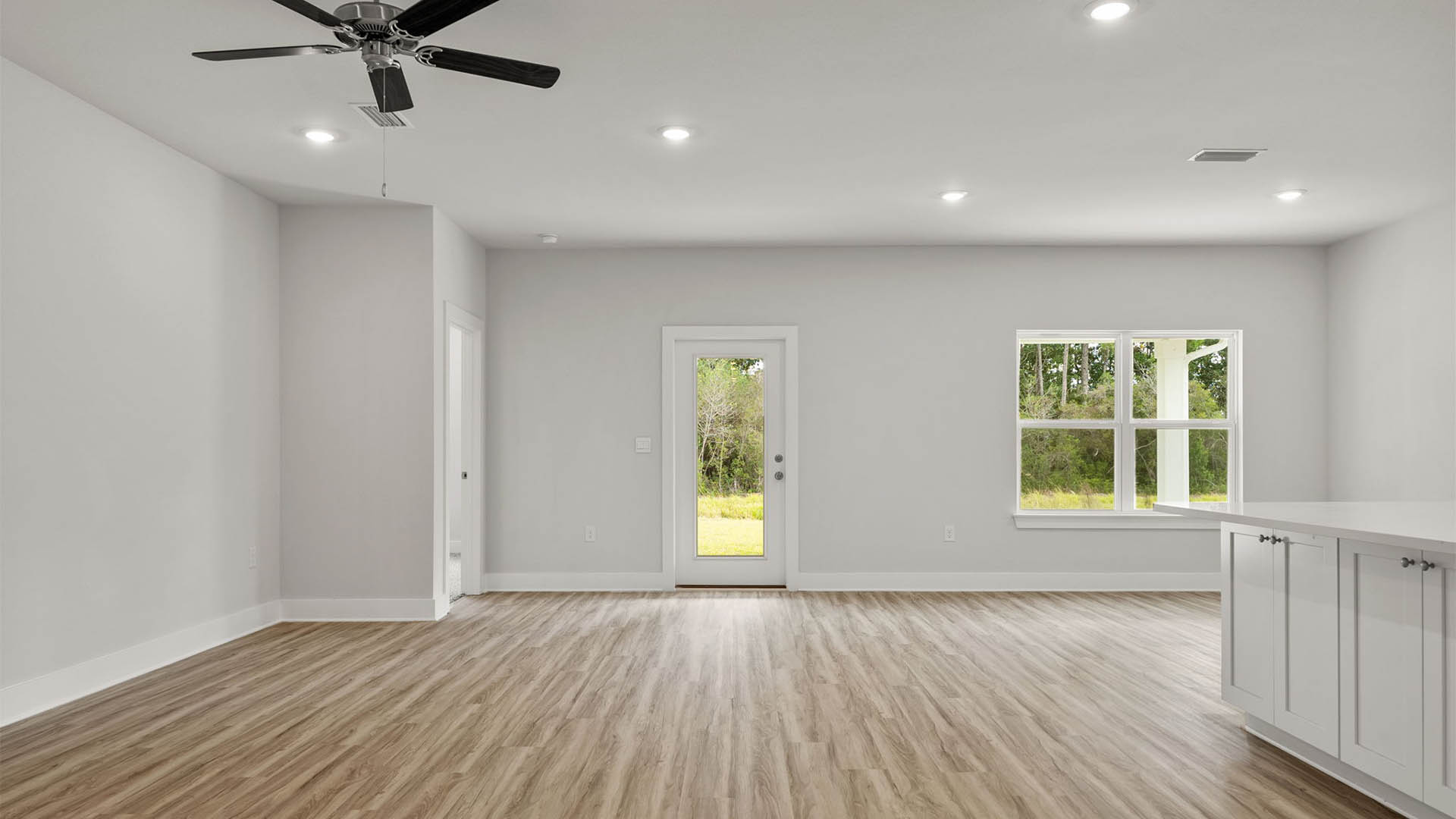 Open Living room with EVP flooring and ceiling fan and back door.