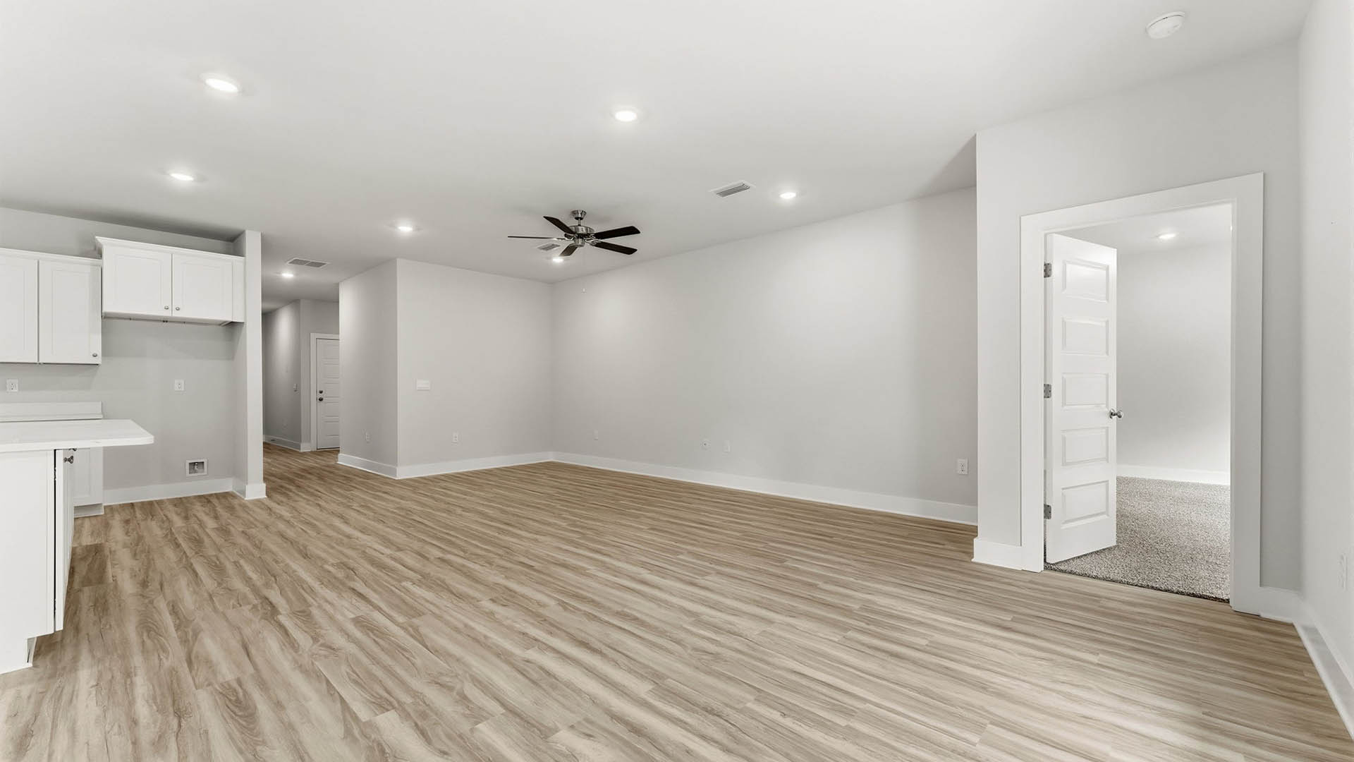 Open Living room with EVP flooring and ceiling fan and kitchen island with quartz countertops.