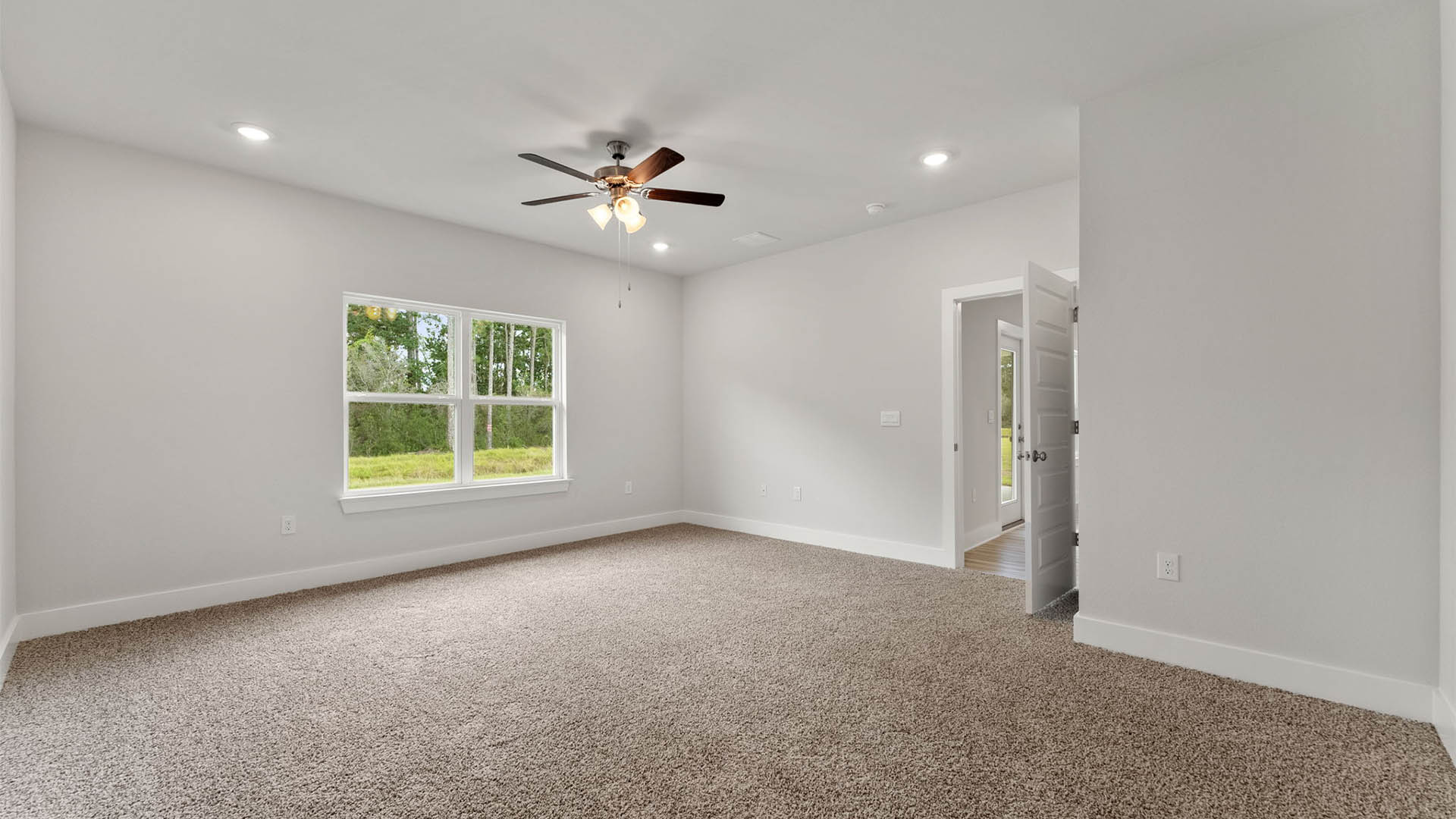 Primary bedroom with carpet floors and ceiling fan and windows.