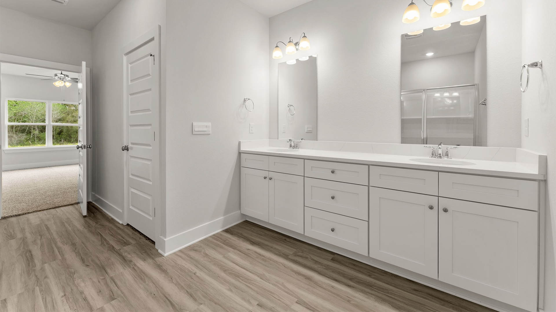 Primary bathroom with EVP flooring with white cabinets and quartz countertops and double vanity.