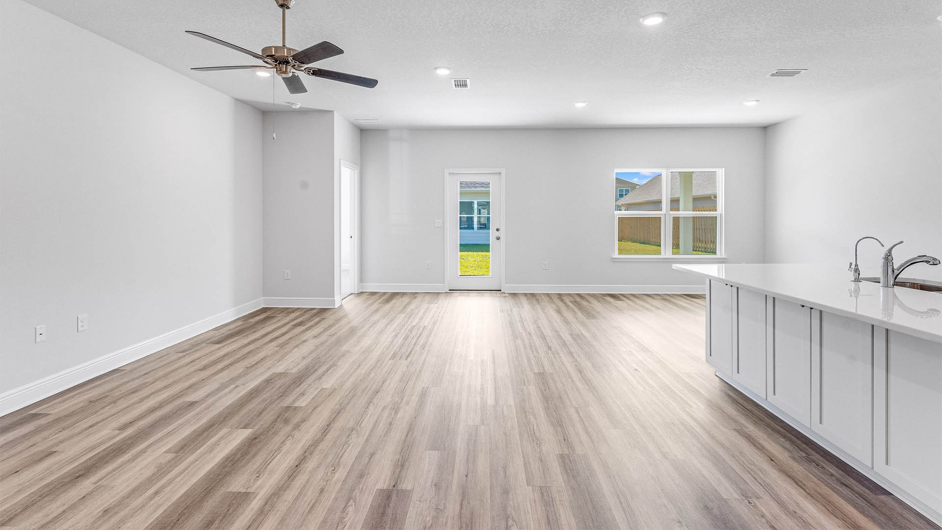 Open Living room with EVP flooring and ceiling fan and kitchen island with quartz countertops.