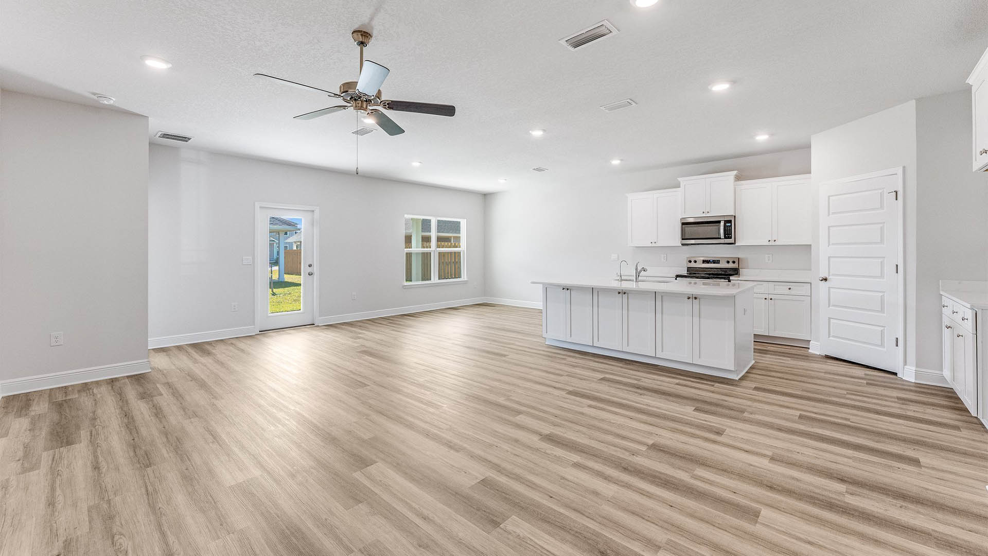 Open Living room with EVP flooring and ceiling fan and kitchen island with quartz countertops.