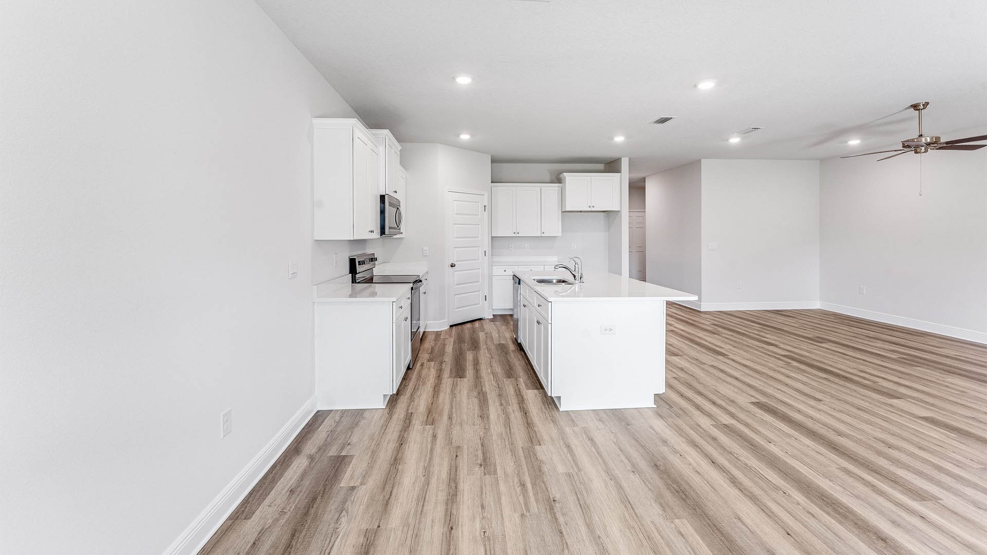 Open Living room with EVP flooring and ceiling fan and kitchen island with quartz countertops.