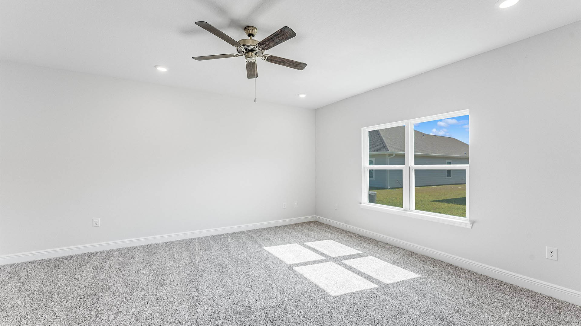 Primary bedroom with carpet floors and ceiling fan and windows.