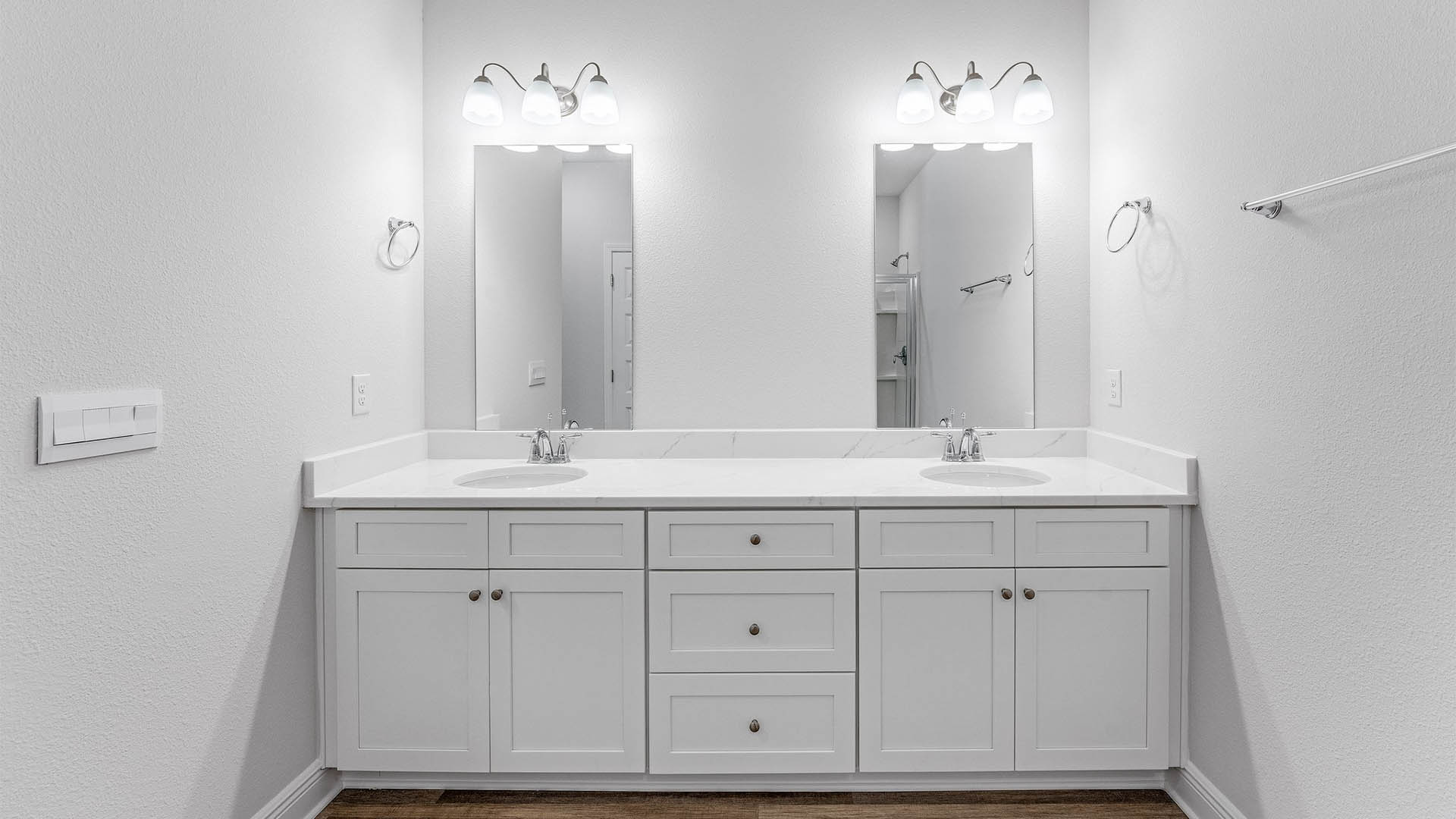 Primary bathroom with EVP flooring with white cabinets and quartz countertops and double vanity.