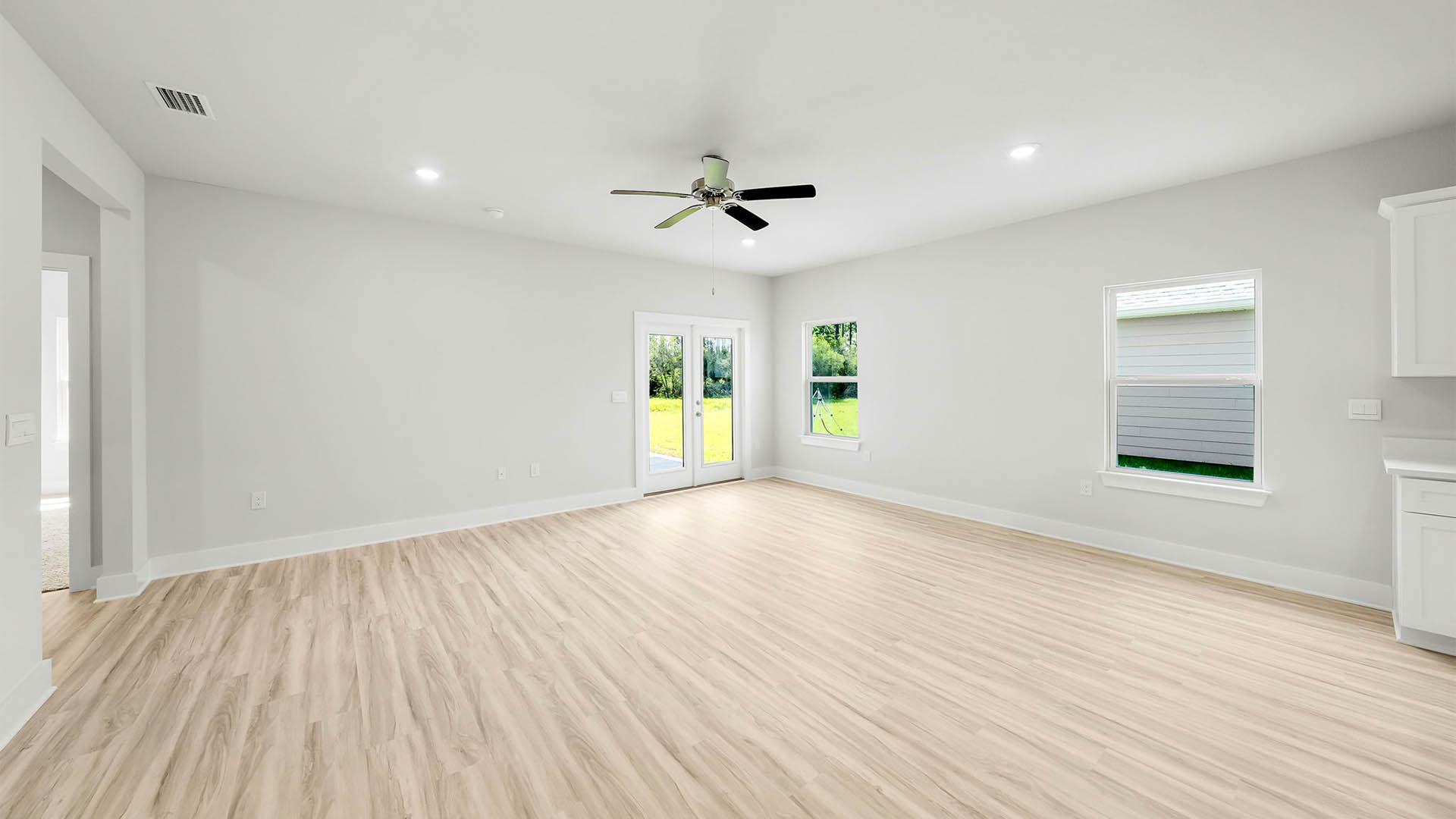 Open Living room with EVP flooring and ceiling fan and windows and back door.
