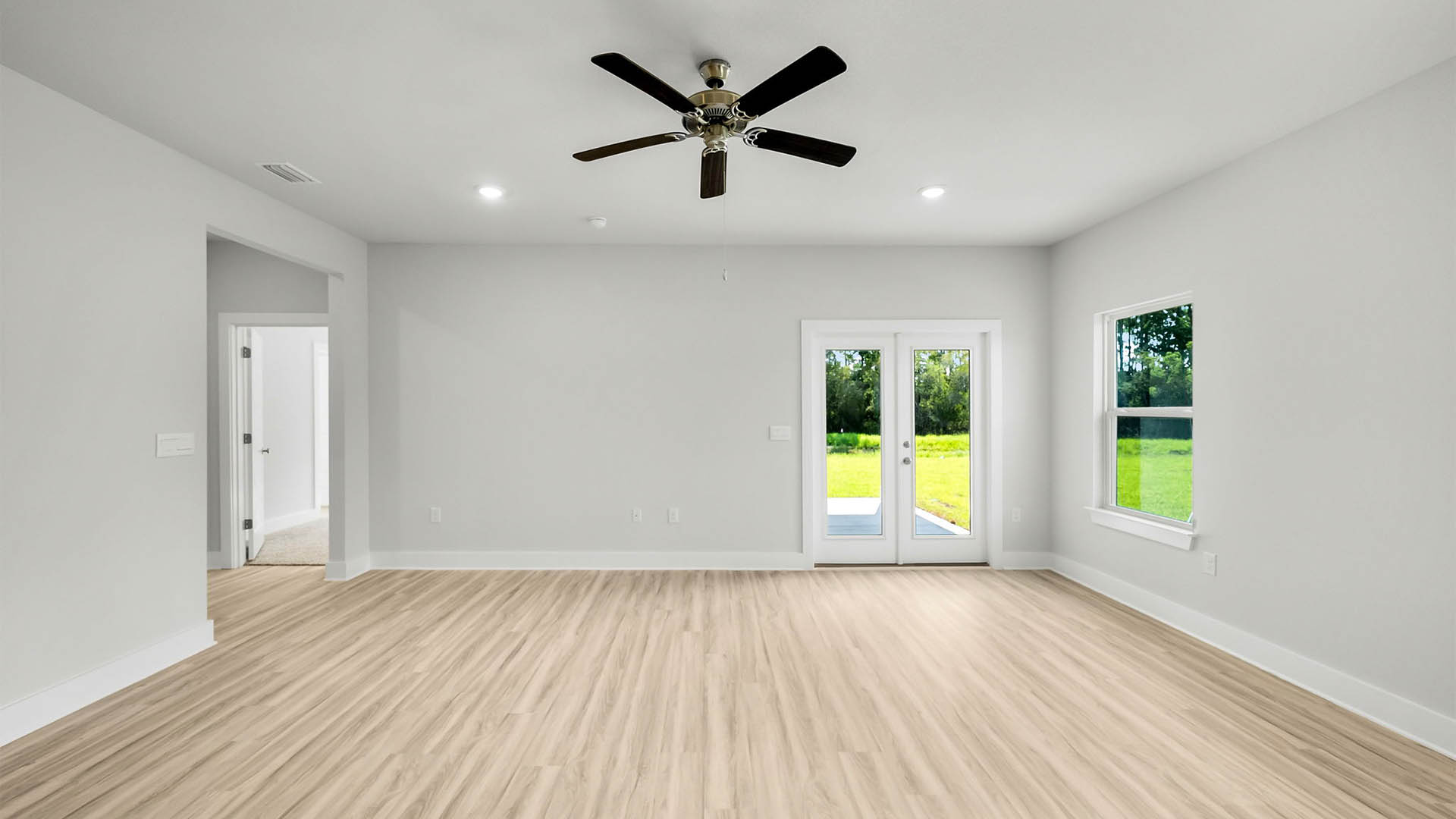 Open Living room with EVP flooring and ceiling fan and windows and back door.