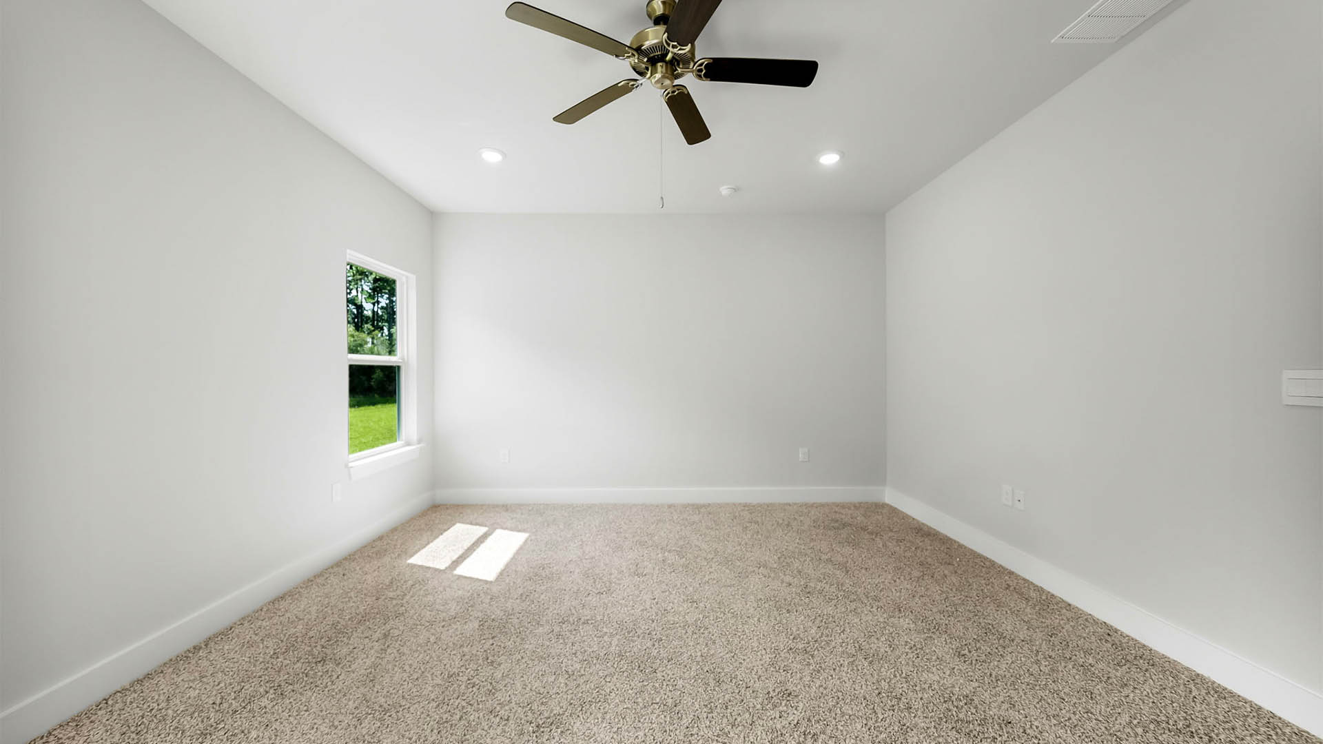 Primary bedroom with carpet flooring and ceiling fan and window.