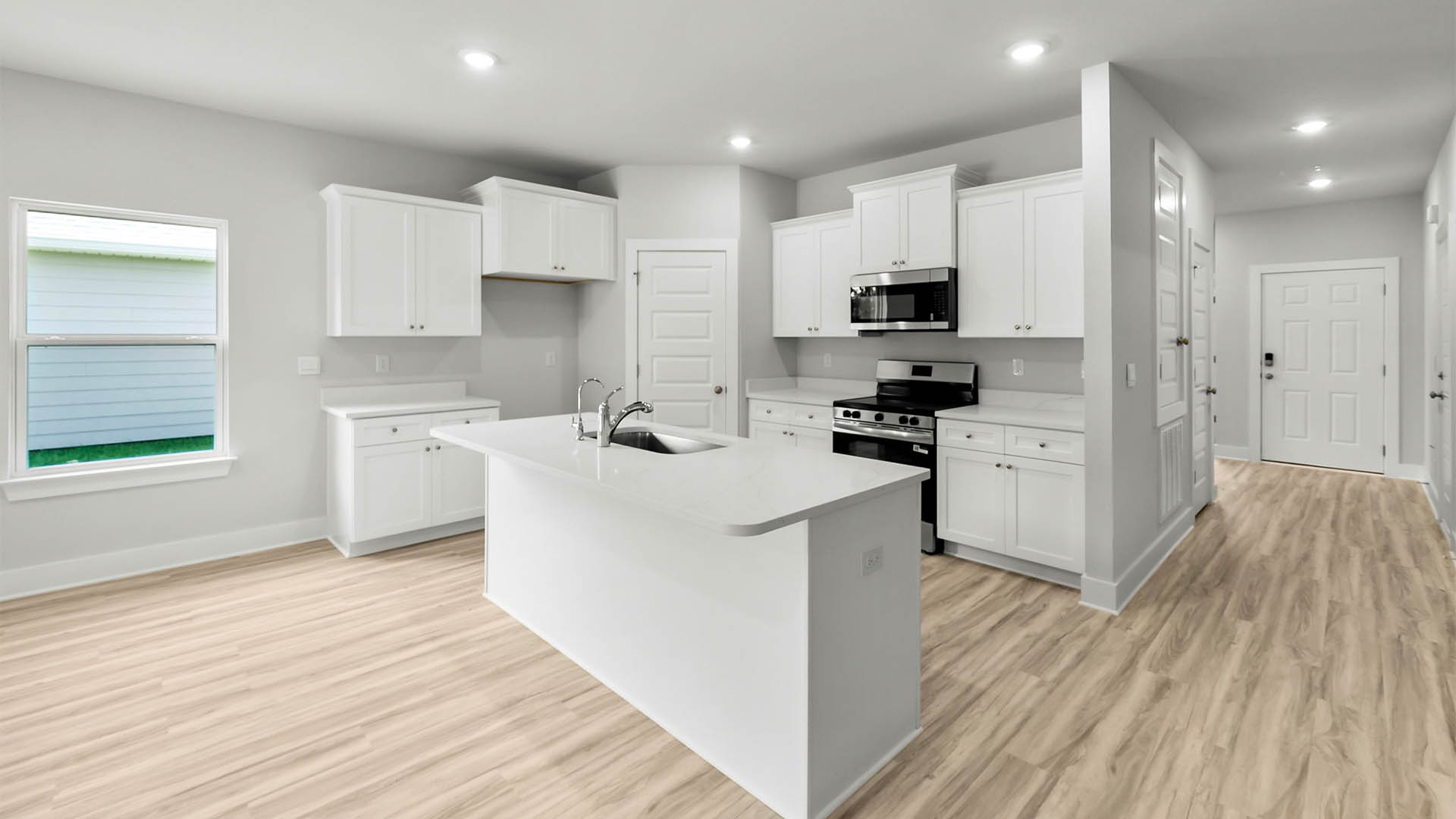 Kitchen with quartz countertops and white cabinetry and island and stainless-steel appliances and pantry.