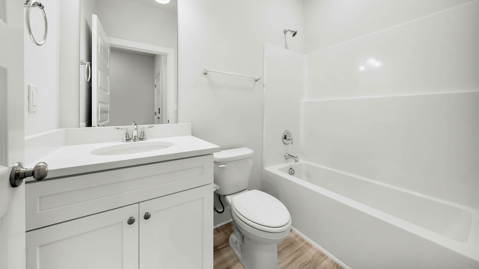 Bathroom with EVP flooring and quartz countertops and single vanity and white cabinets and tub and shower.