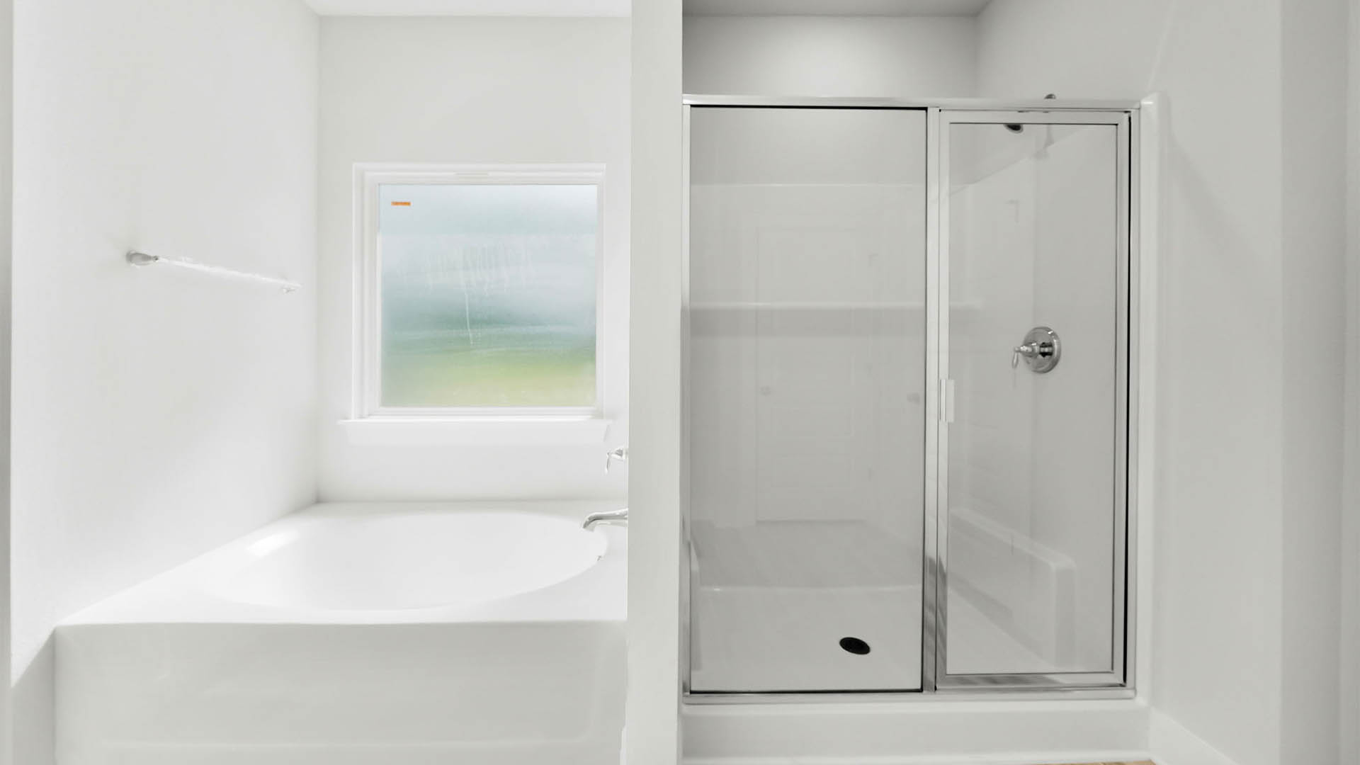 Primary bathroom with glass shower doors and tub with window.