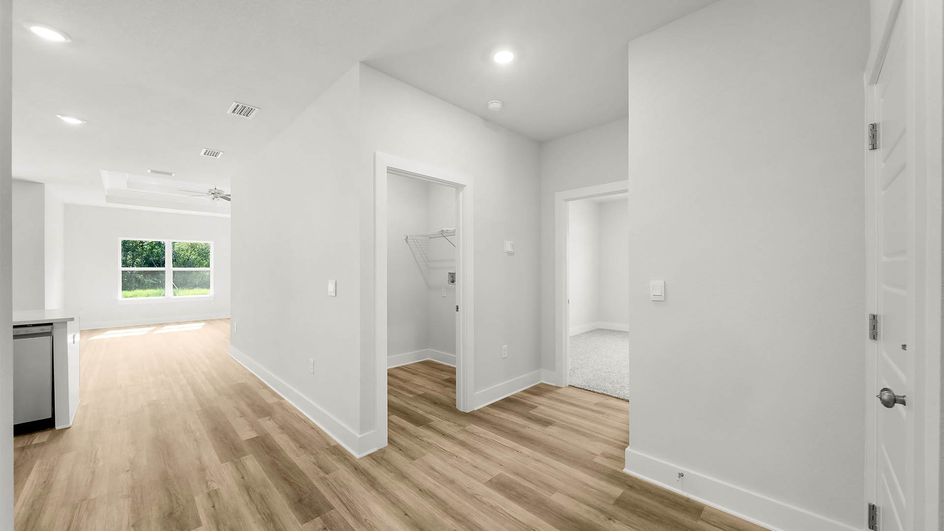 Hallway next to garage entrance and laundry room and bedroom and kitchen.