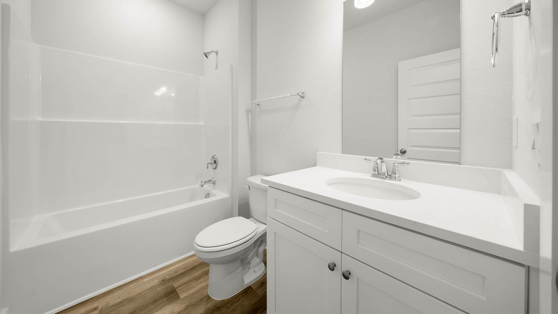 Bathroom with single vanity quartz countertops and white cabinets and toilet and shower.