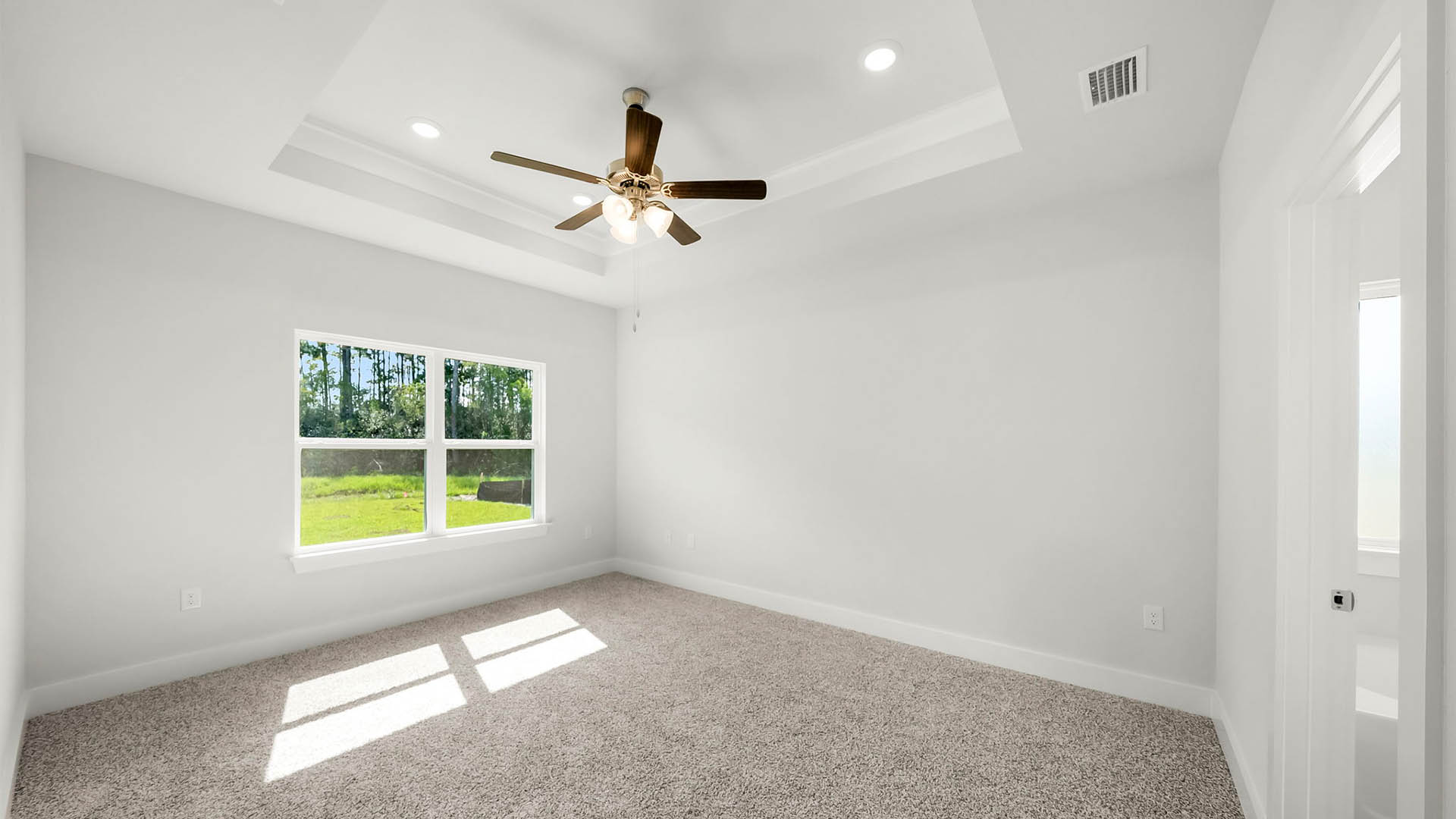 Primary bedroom with carpet floor and tray ceilings and ceiling fan and two windows.