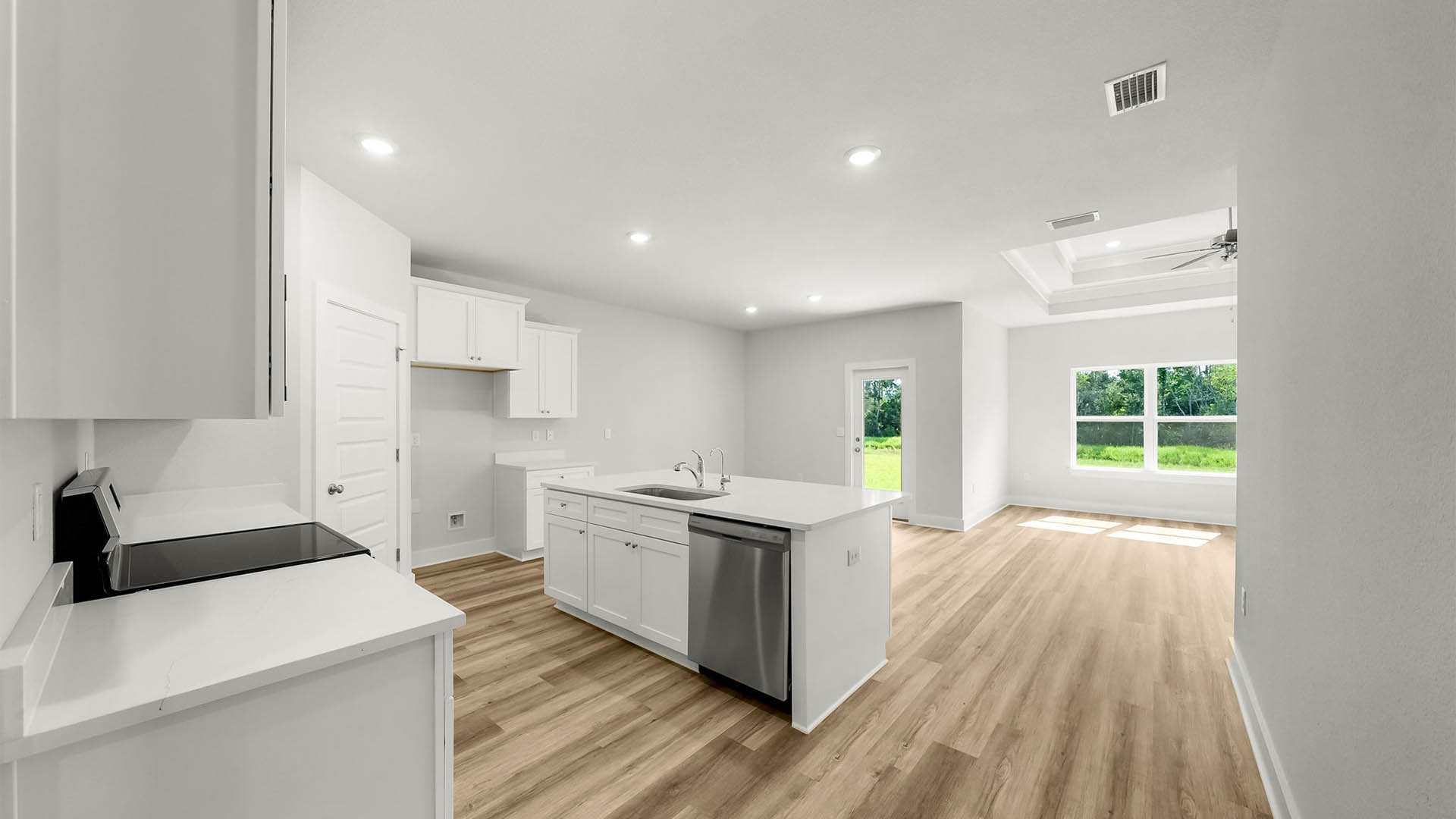 Kitchen with quartz countertops and white cabinetry and island and stainless-steel appliances and pantry.
