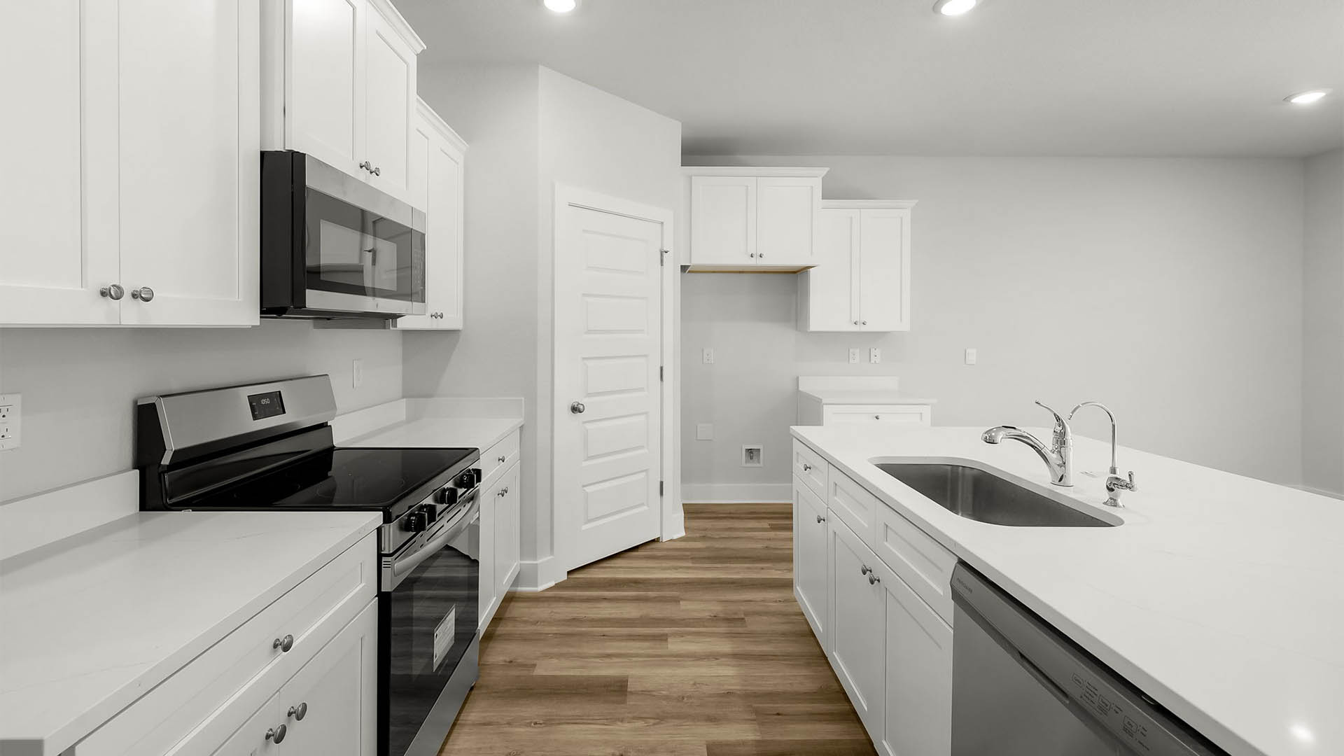 Kitchen with quartz countertops and white cabinetry and island and stainless-steel appliances and pantry.
