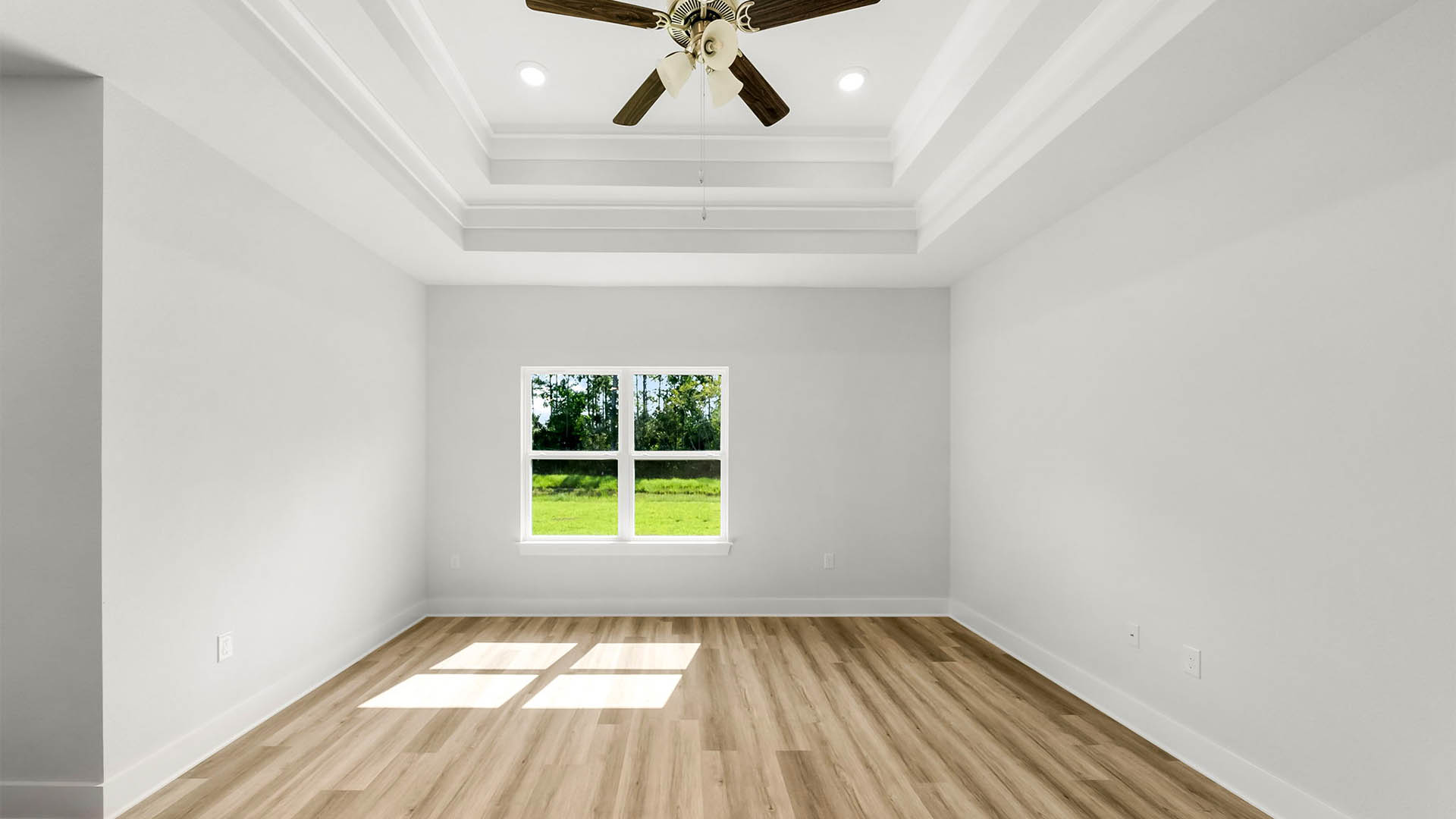Living room with EVP flooring and tray ceilings and ceiling fan and two windows.