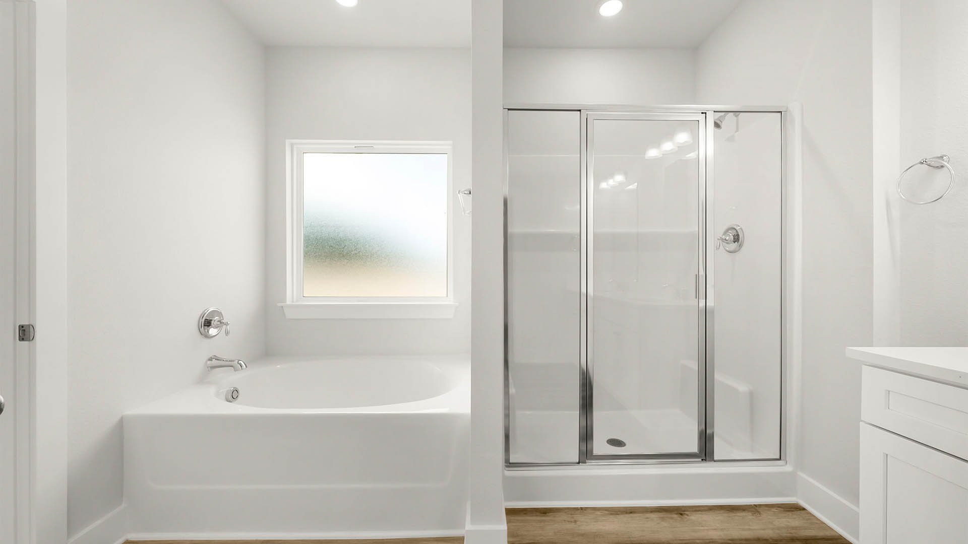 Primary bathroom with glass shower doors and tub with window.