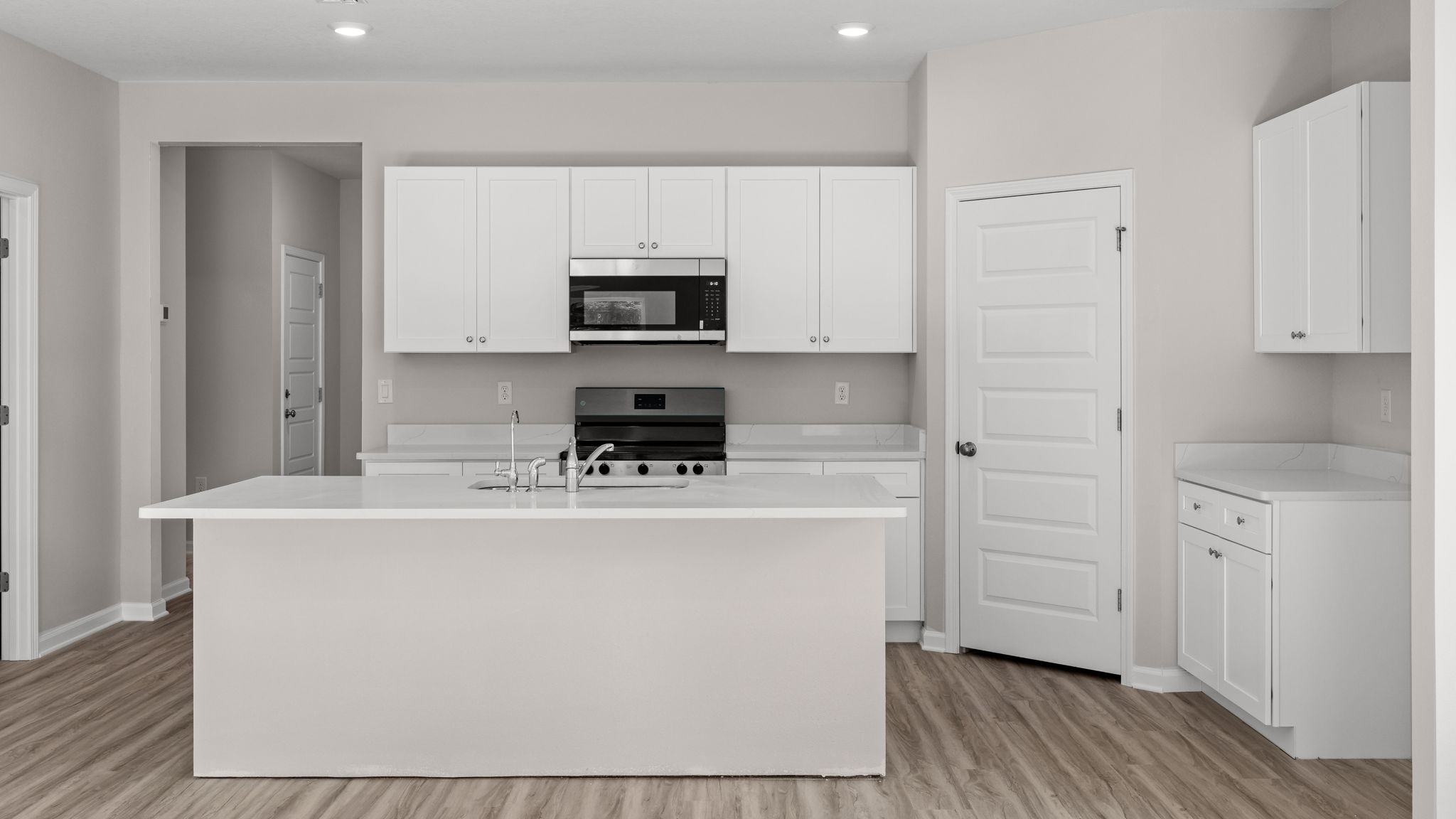 Kitchen with island and quartz countertops with white cabinets and stainless-steel appliances.