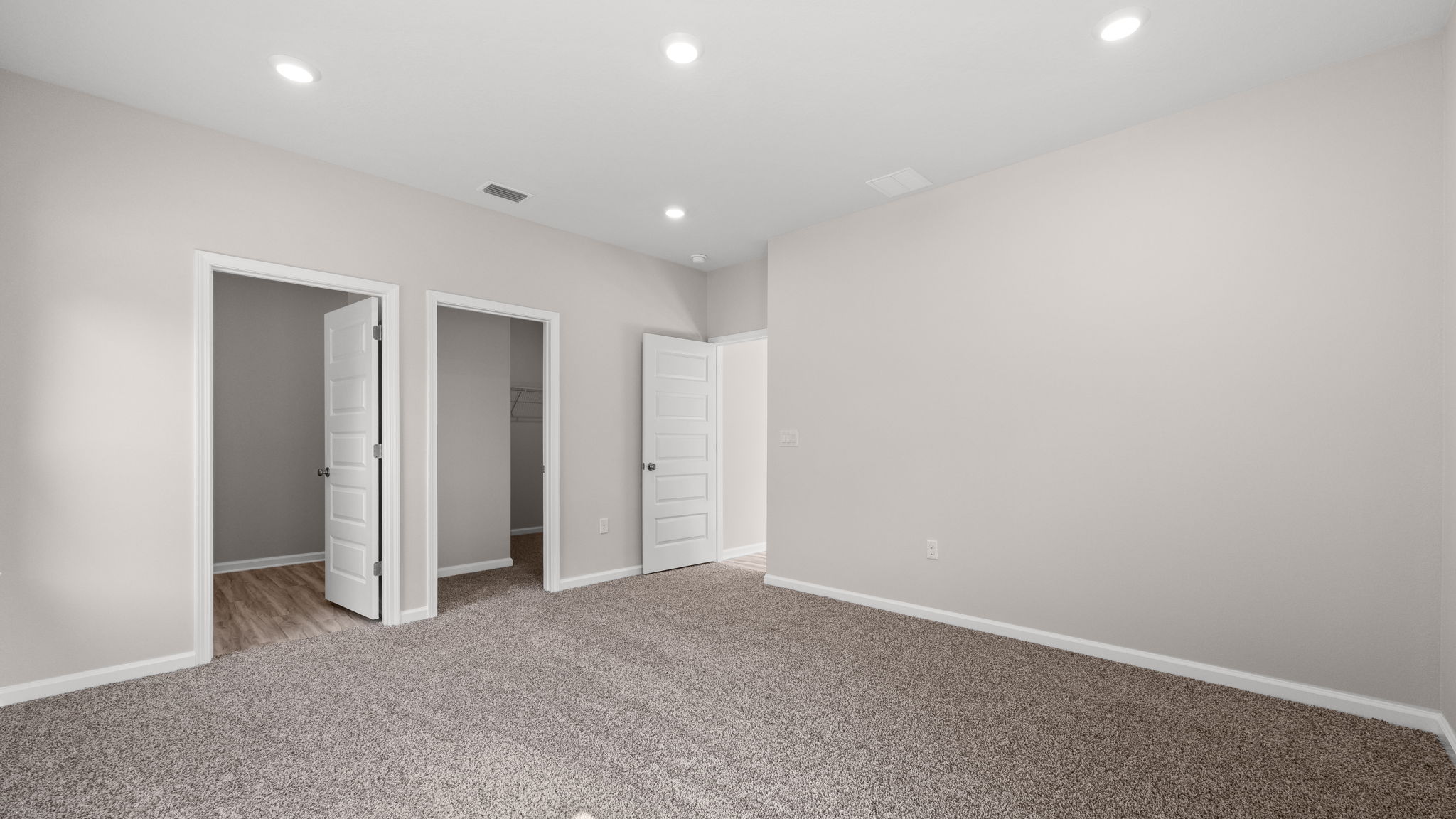 Primary bedroom with carpet floors and bathroom entrance.