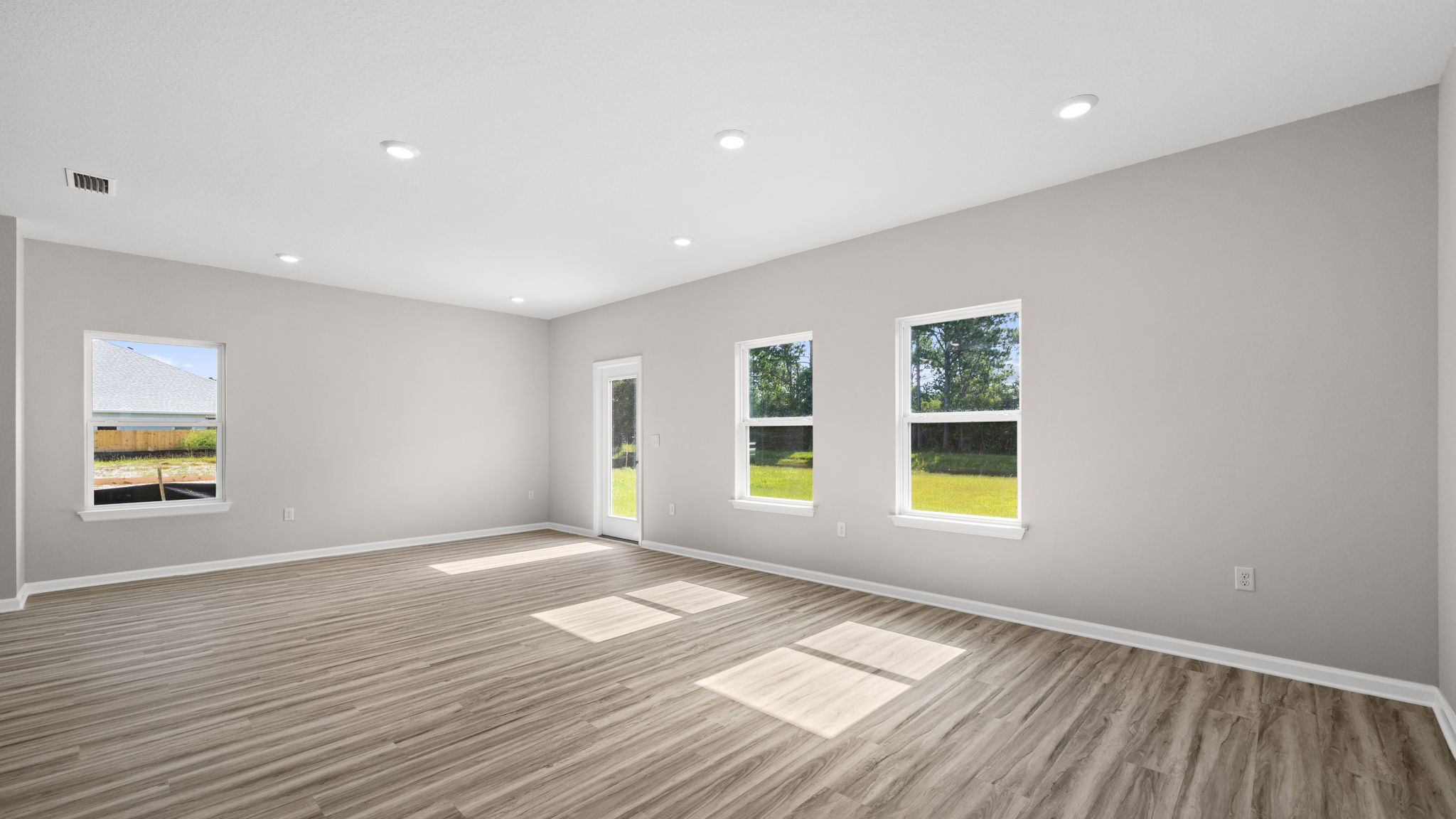Living room with EVP flooring and dining area and back door and windows.