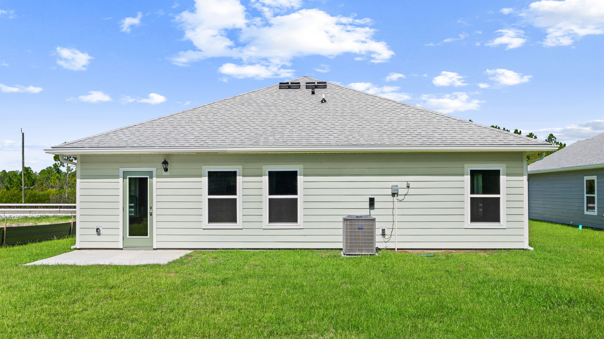Walker plan rear of home with concrete pad and back yard.
