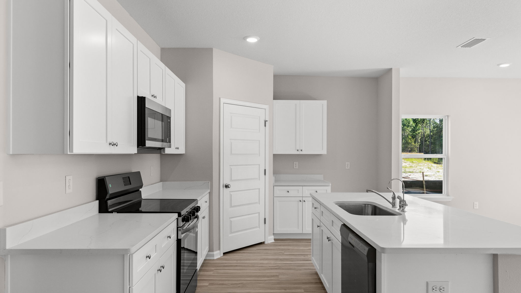 Kitchen with island and quartz countertops with white cabinets and stainless-steel appliances.