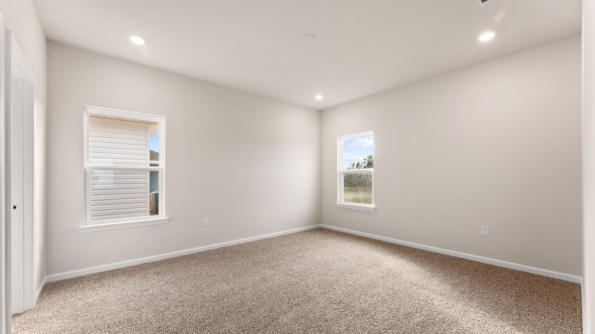 Primary bedroom with carpet flooring and windows.