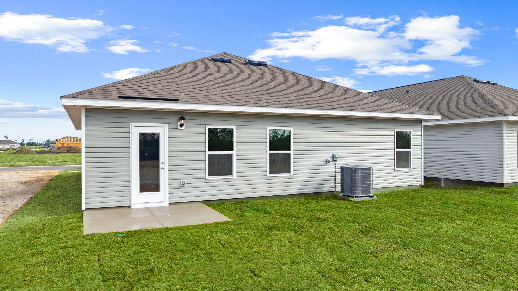 Walker plan rear of home with concrete pad and back yard.