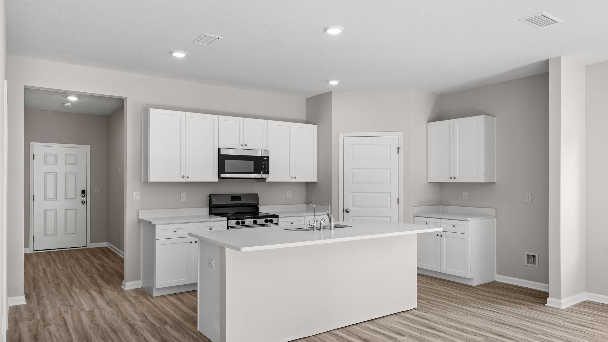 Kitchen with island and quartz countertops with white cabinets and stainless-steel appliances.