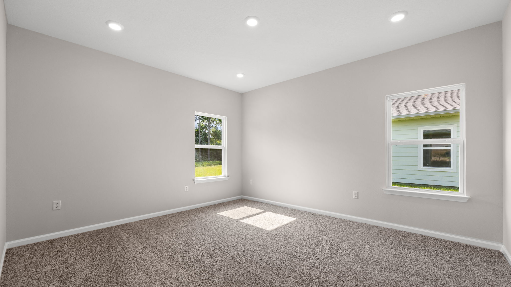 Primary bedroom with carpet flooring and windows.