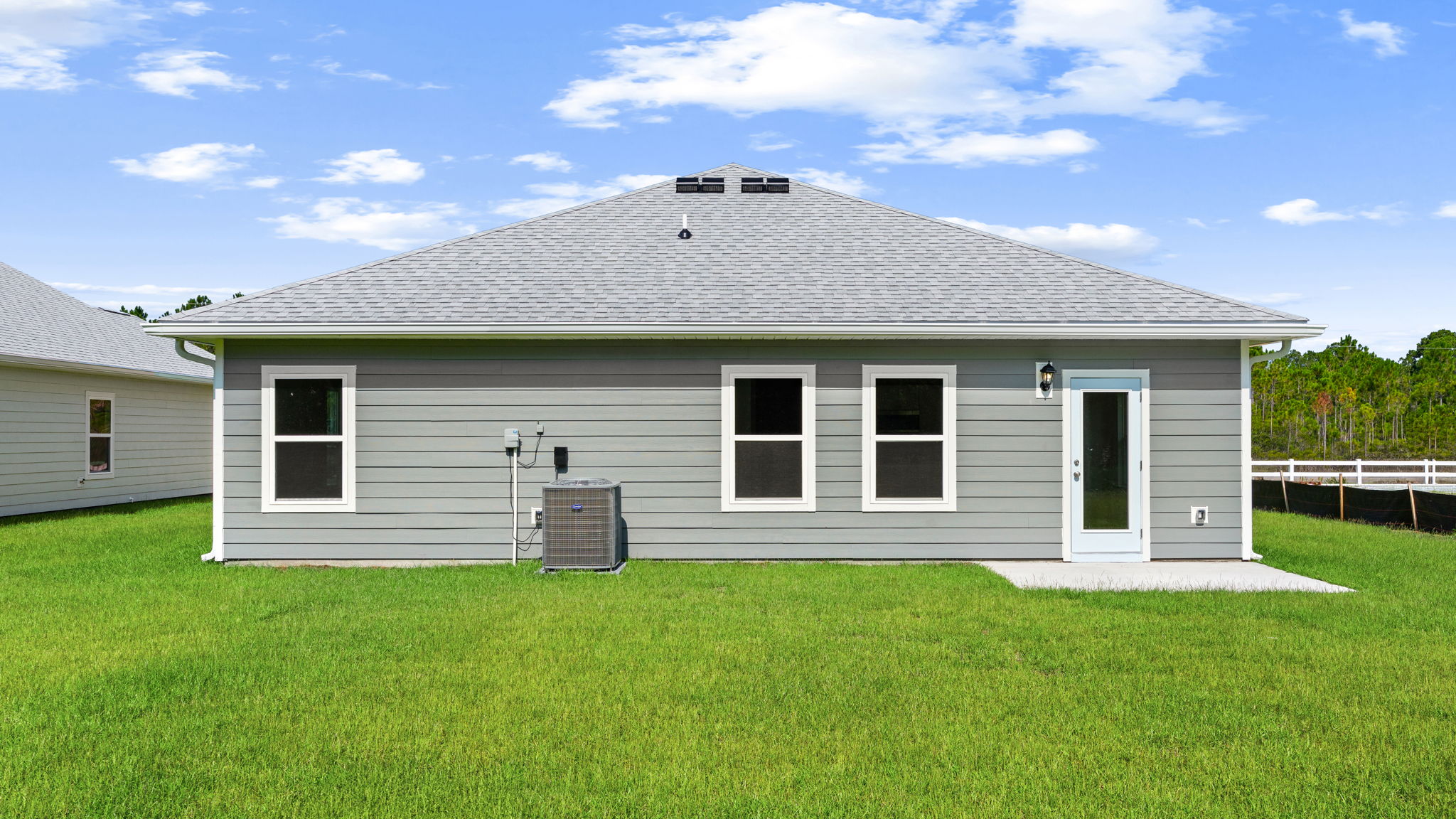 Walker plan rear of home with concrete pad and back yard.