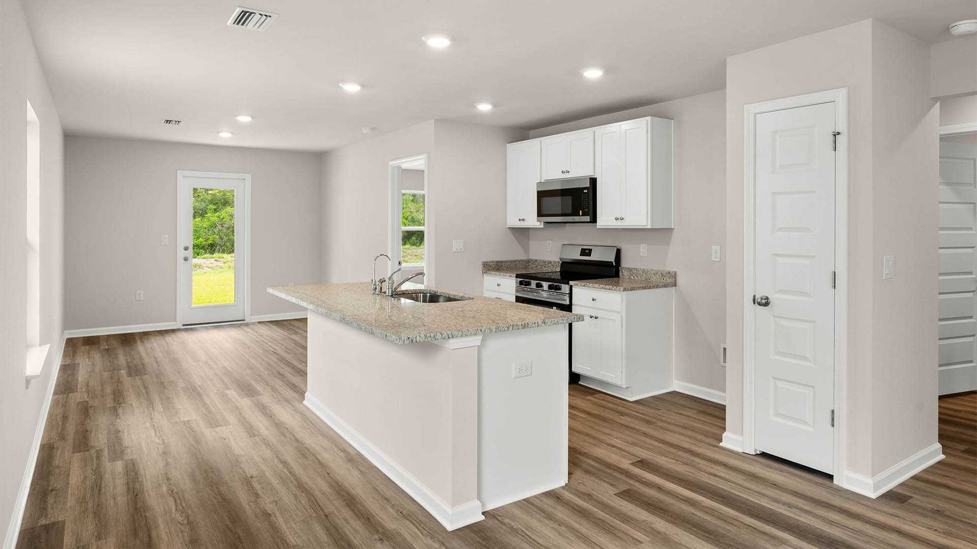 Open kitchen with center island with granite countertops and stainless-steel appliances and closet pantry and white cabinets.