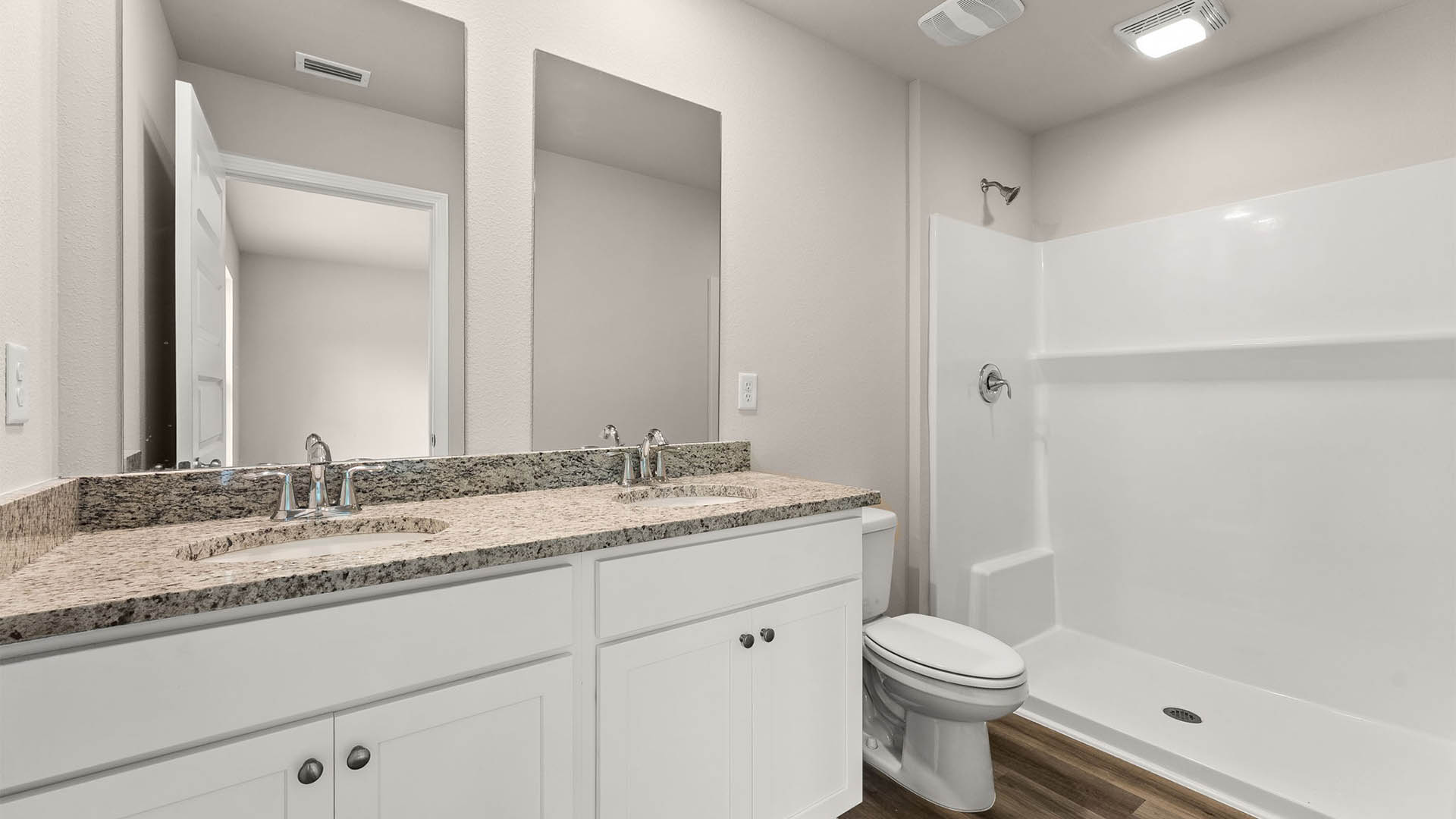 Primary bathroom with double vanity granite countertops and toilet and shower and EVP flooring.