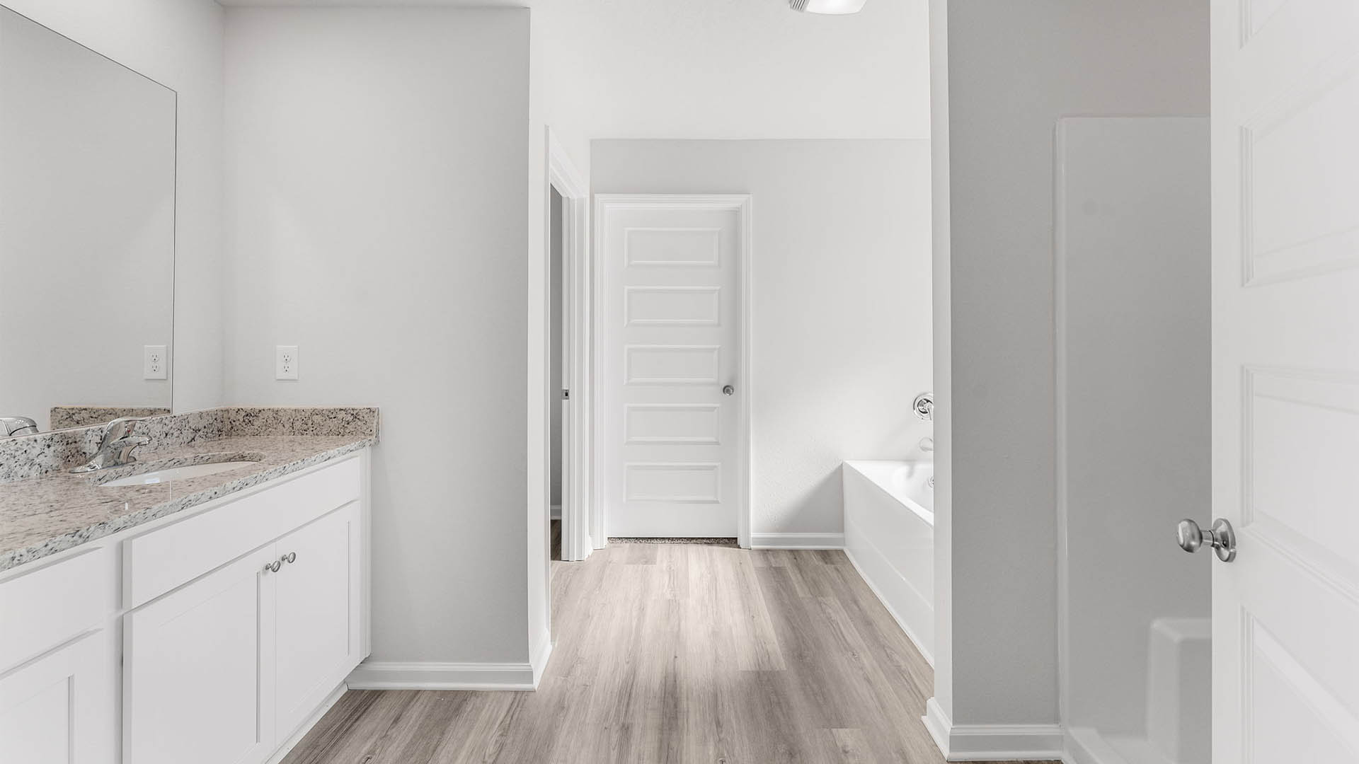 Primary bathroom with double vanity granite countertops and closet entrance.
